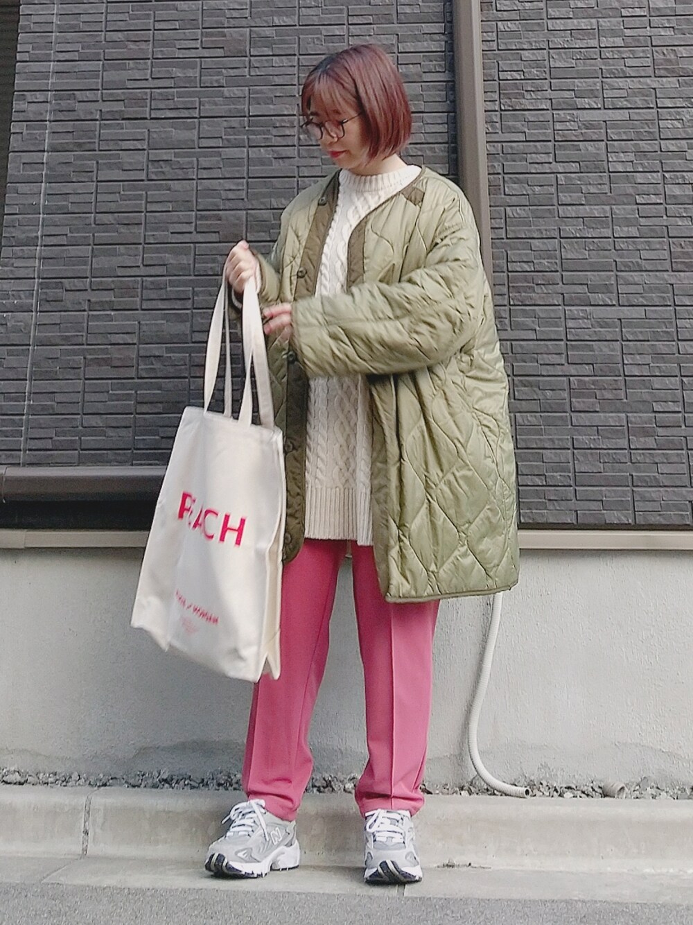 グリーン系のミリタリージャケット、ホワイト系のニット/セーター、その他のトートバッグを着用したレディースの冬コーディネートの2枚目の写真