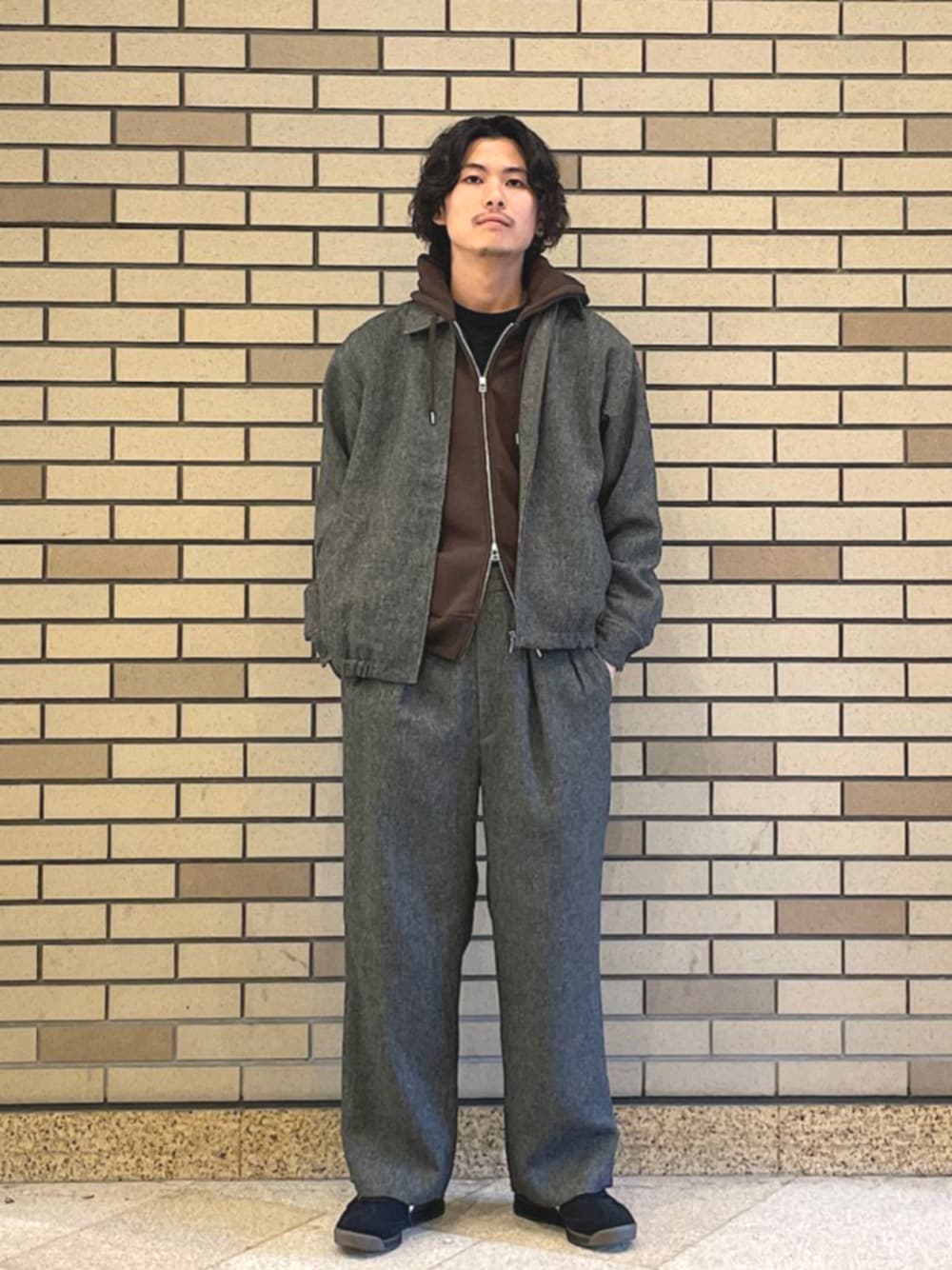 ブラウン系のパーカー、グレー系のスラックス、ブラック系のスニーカーを着用したメンズの秋コーディネートの1枚目の写真