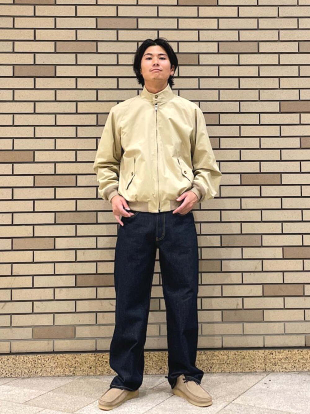 ベージュ系のブルゾン、ブルー系のデニムパンツ、グリーン系のスニーカーを着用したメンズの秋コーディネートの1枚目の写真