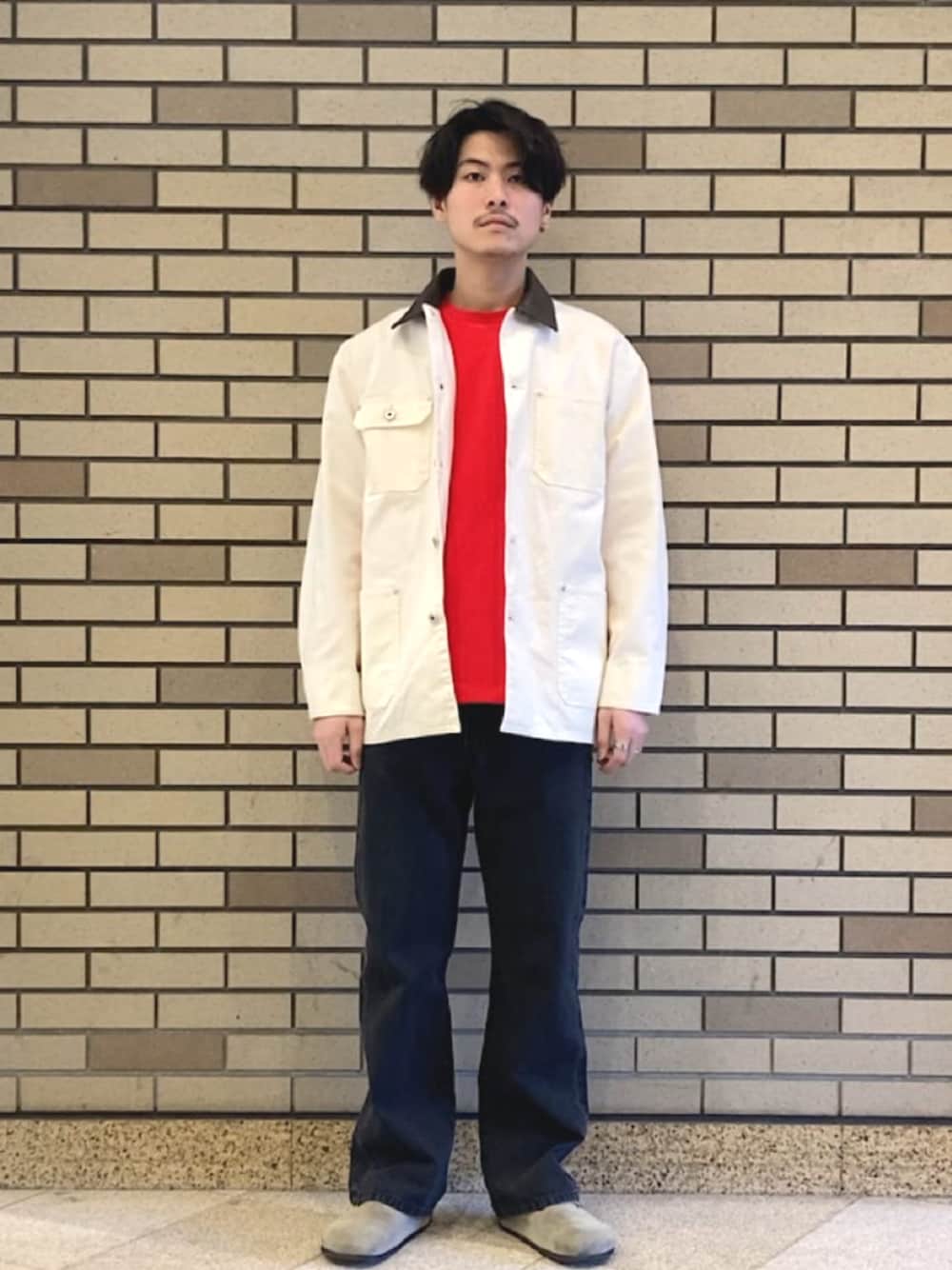 ブラック系のデニムパンツ、ベージュ系のブルゾン、レッド系のTシャツ/カットソーを着用したメンズの春コーディネートの1枚目の写真