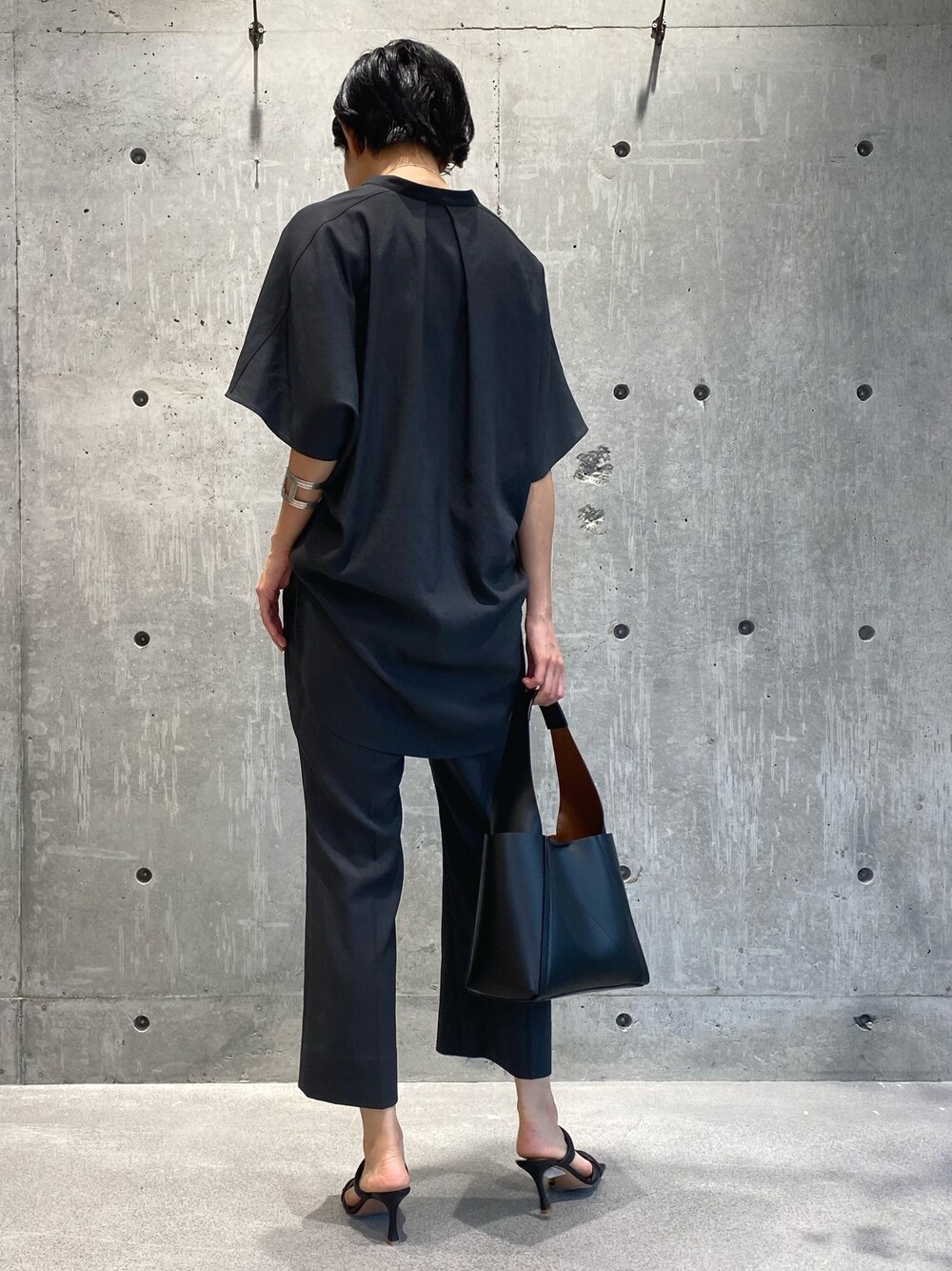 グレー系のシャツ/ブラウス、グレー系のスラックス、ブラック系のサンダルを着用したレディースの夏コーディネートの3枚目の写真