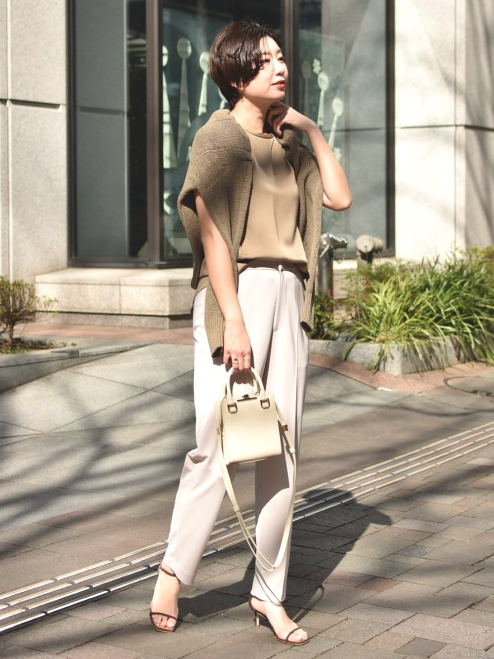 ブラウン系のニット/セーター、ブラウン系のTシャツ/カットソー、ベージュ系のパンツを着用したレディースの春コーディネートの1枚目の写真