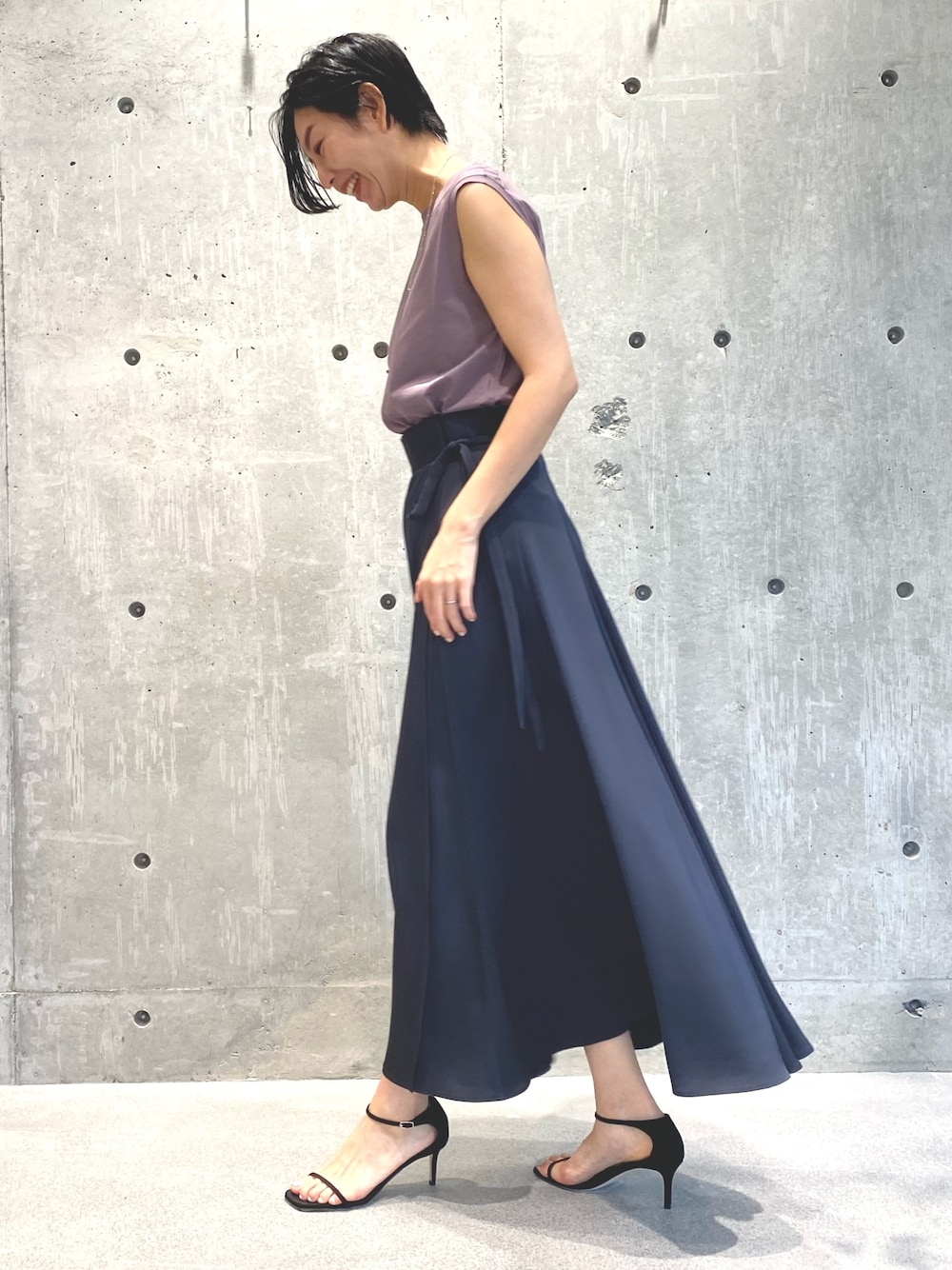 グレー系のスカート、ピンク系のTシャツ/カットソー、シルバー系のネックレスを着用したレディースの春コーディネートの2枚目の写真