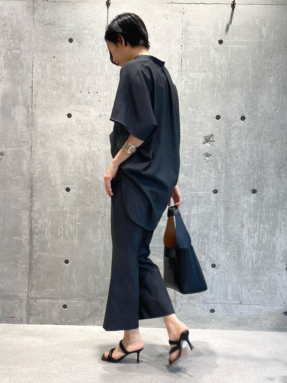 グレー系のシャツ/ブラウス、グレー系のスラックス、ブラック系のサンダルを着用したレディースの夏コーディネートの2枚目の写真