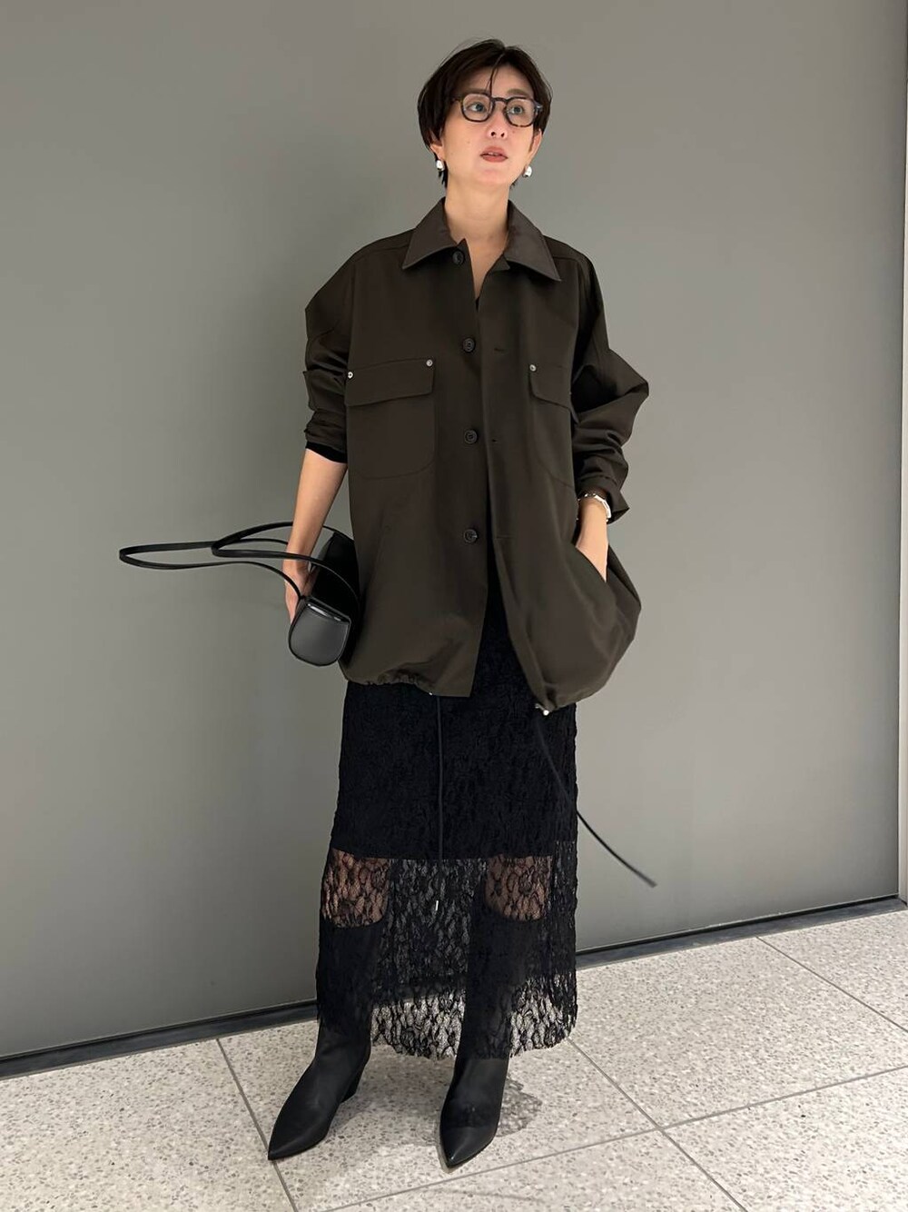 ブラック系のTシャツ/カットソー、ブラウン系のステンカラーコート、ブラック系のスカートを着用したレディースの夏コーディネートの1枚目の写真