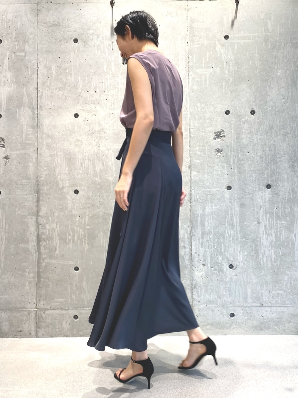 グレー系のスカート、ピンク系のTシャツ/カットソー、シルバー系のネックレスを着用したレディースの春コーディネートの3枚目の写真