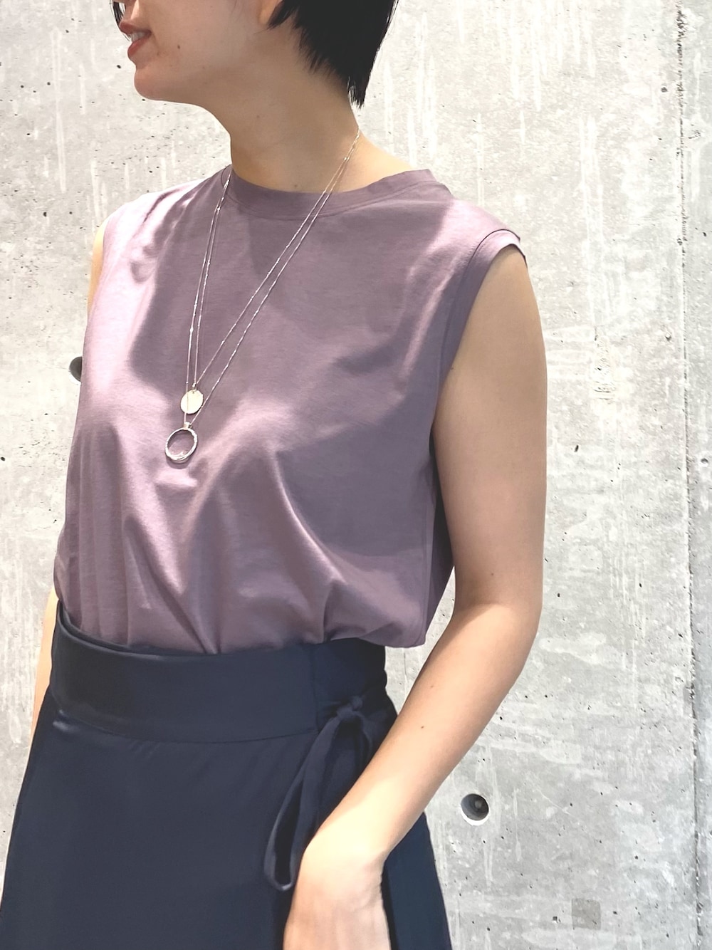 グレー系のスカート、ピンク系のTシャツ/カットソー、シルバー系のネックレスを着用したレディースの春コーディネートの4枚目の写真