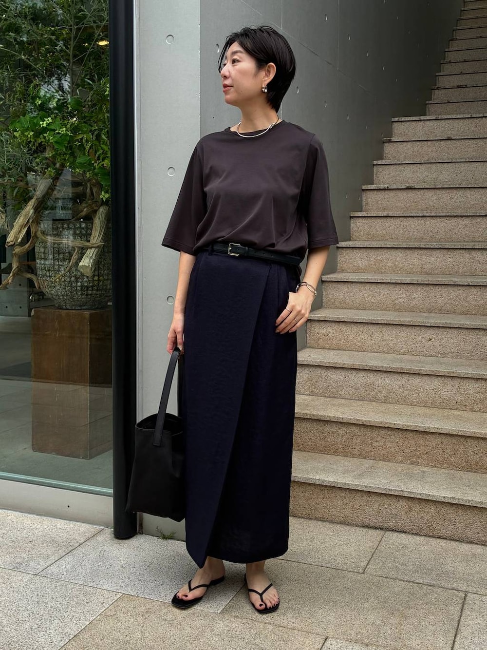 ブルー系のスカート、ブラック系のサンダル、ブラウン系のTシャツ/カットソーを着用したレディースの春コーディネートの1枚目の写真