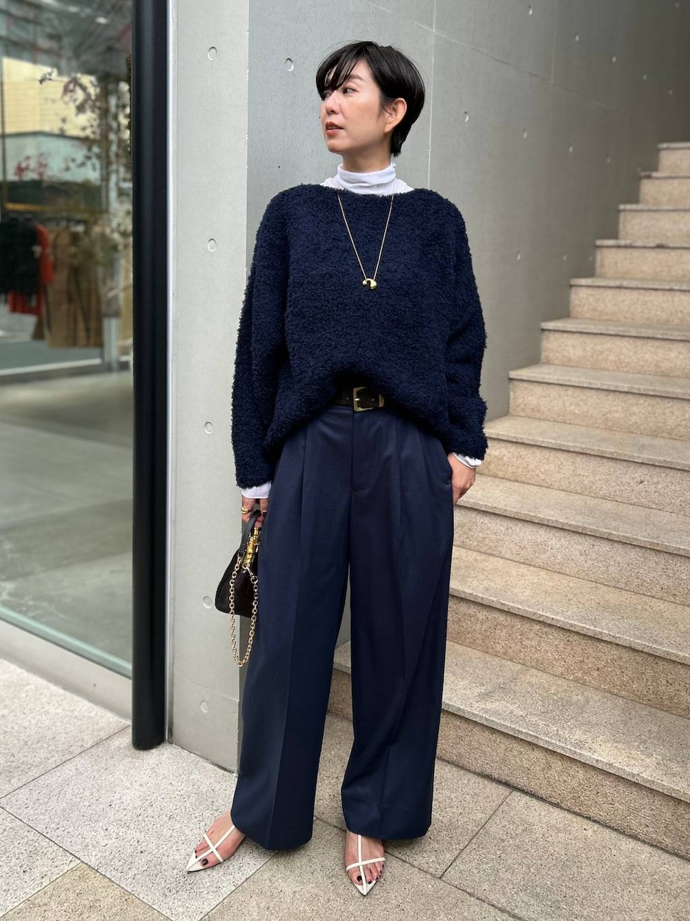 ブルー系のニット/セーター、ホワイト系のその他トップス、ブルー系のスラックスを着用したレディースの秋コーディネートの1枚目の写真