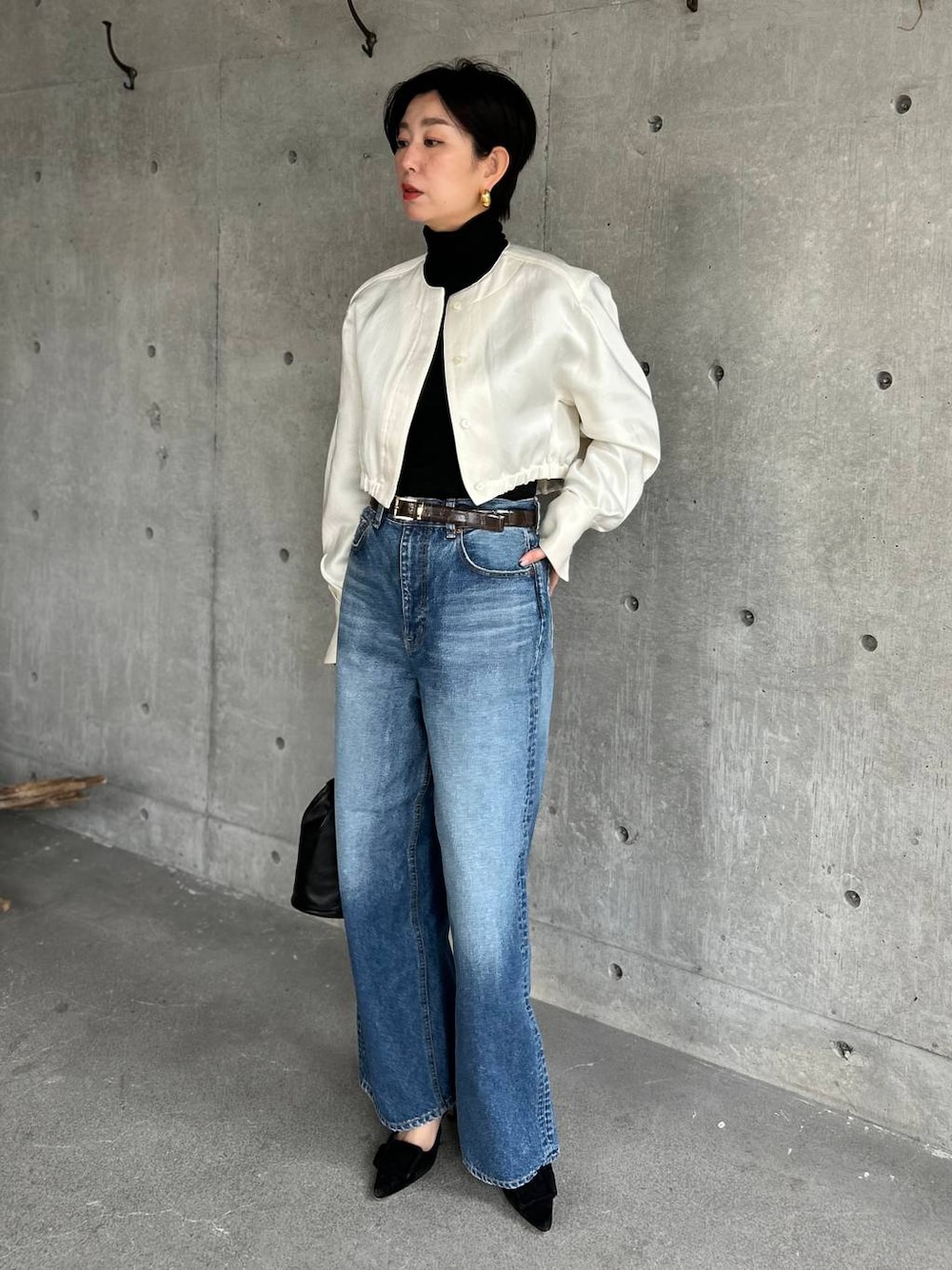 ブラック系のニット/セーター、ブルー系のデニムパンツ、ホワイト系のシャツ/ブラウスを着用したレディースの冬コーディネートの1枚目の写真