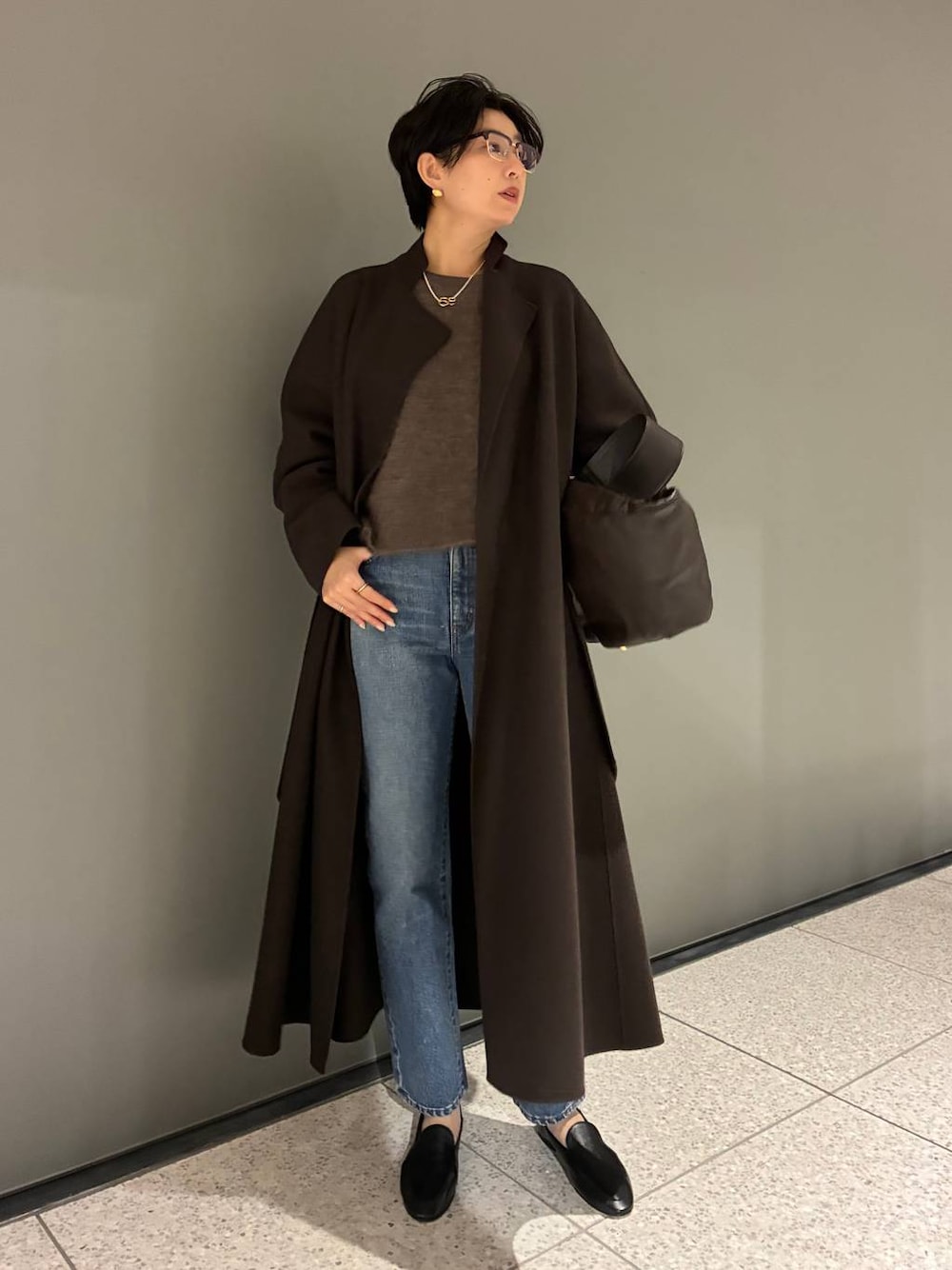 ブルー系のデニムパンツ、ブラウン系のニット/セーター、ブラウン系のノーカラーコートを着用したレディースの秋コーディネートの1枚目の写真