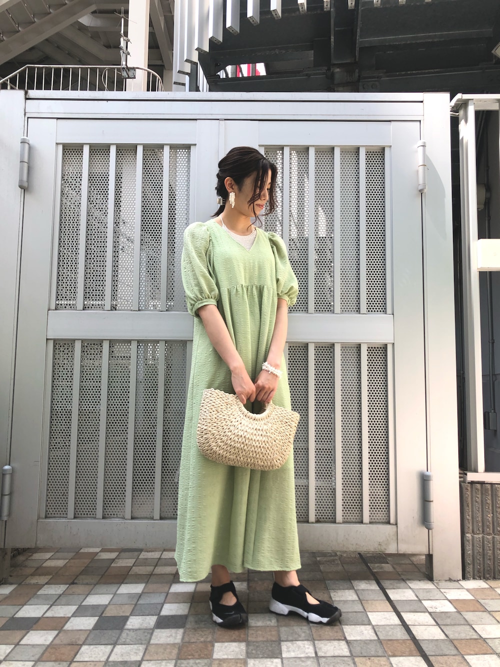 グリーン系のワンピース、グレー系のニット/セーター、ホワイト系のイヤリングを着用したレディースの春コーディネートの1枚目の写真