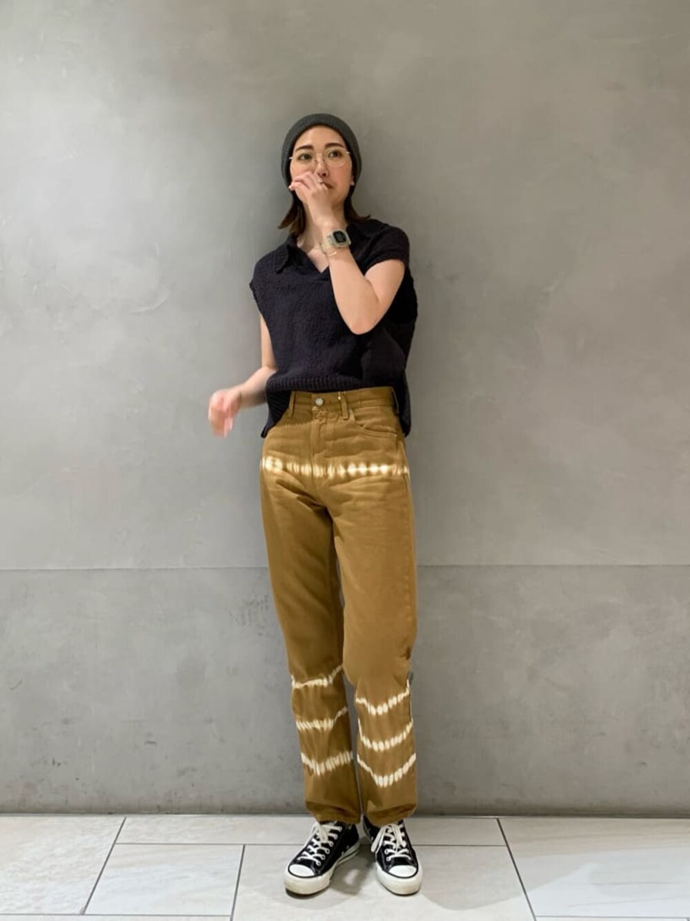 ブラウン系のデニムパンツ、グレー系のベストを着用したレディースの春コーディネートの1枚目の写真