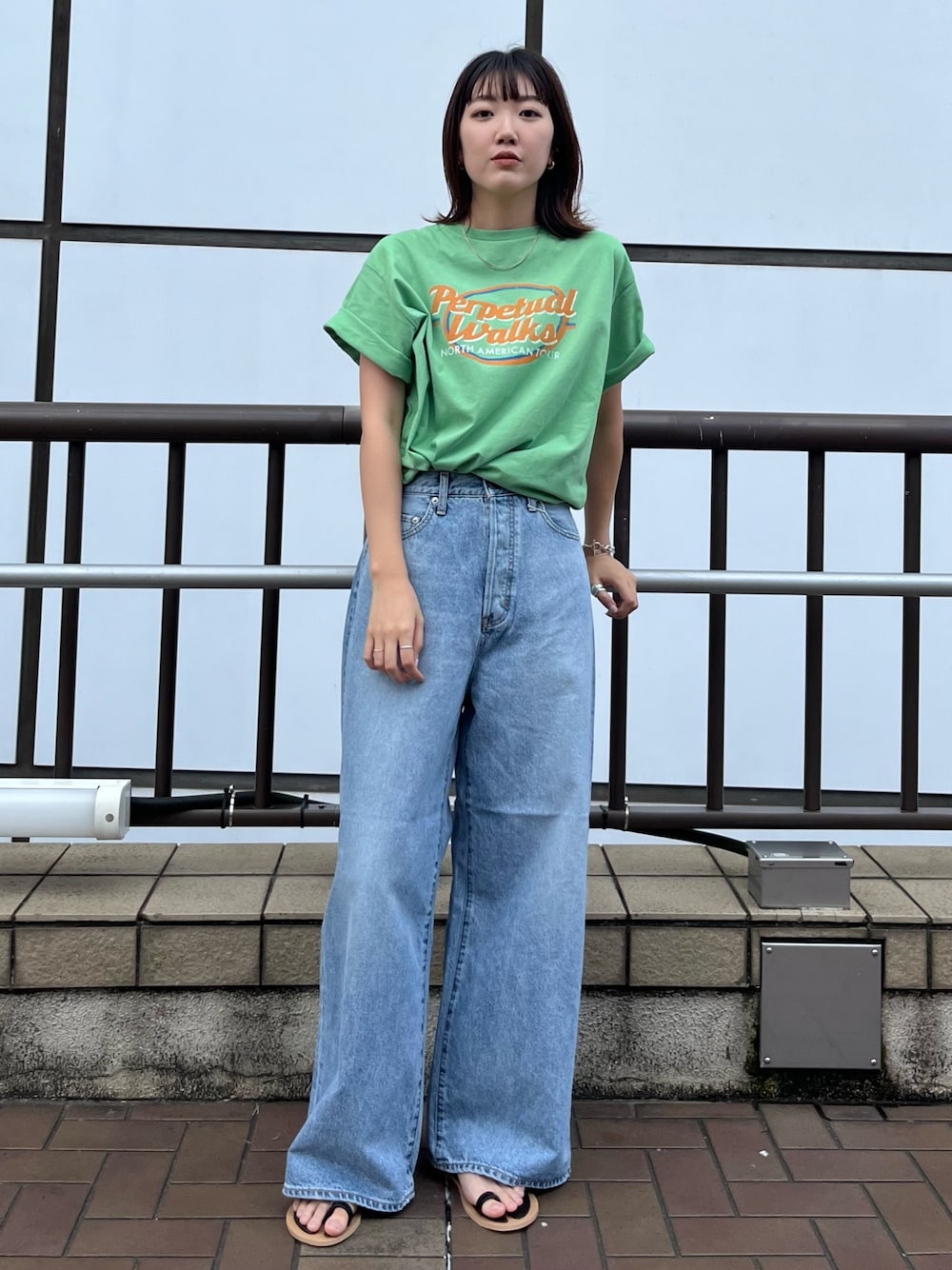 ブラック系のサンダル、グリーン系のTシャツ/カットソー、ブルー系のデニムパンツを着用したレディースの夏コーディネートの1枚目の写真