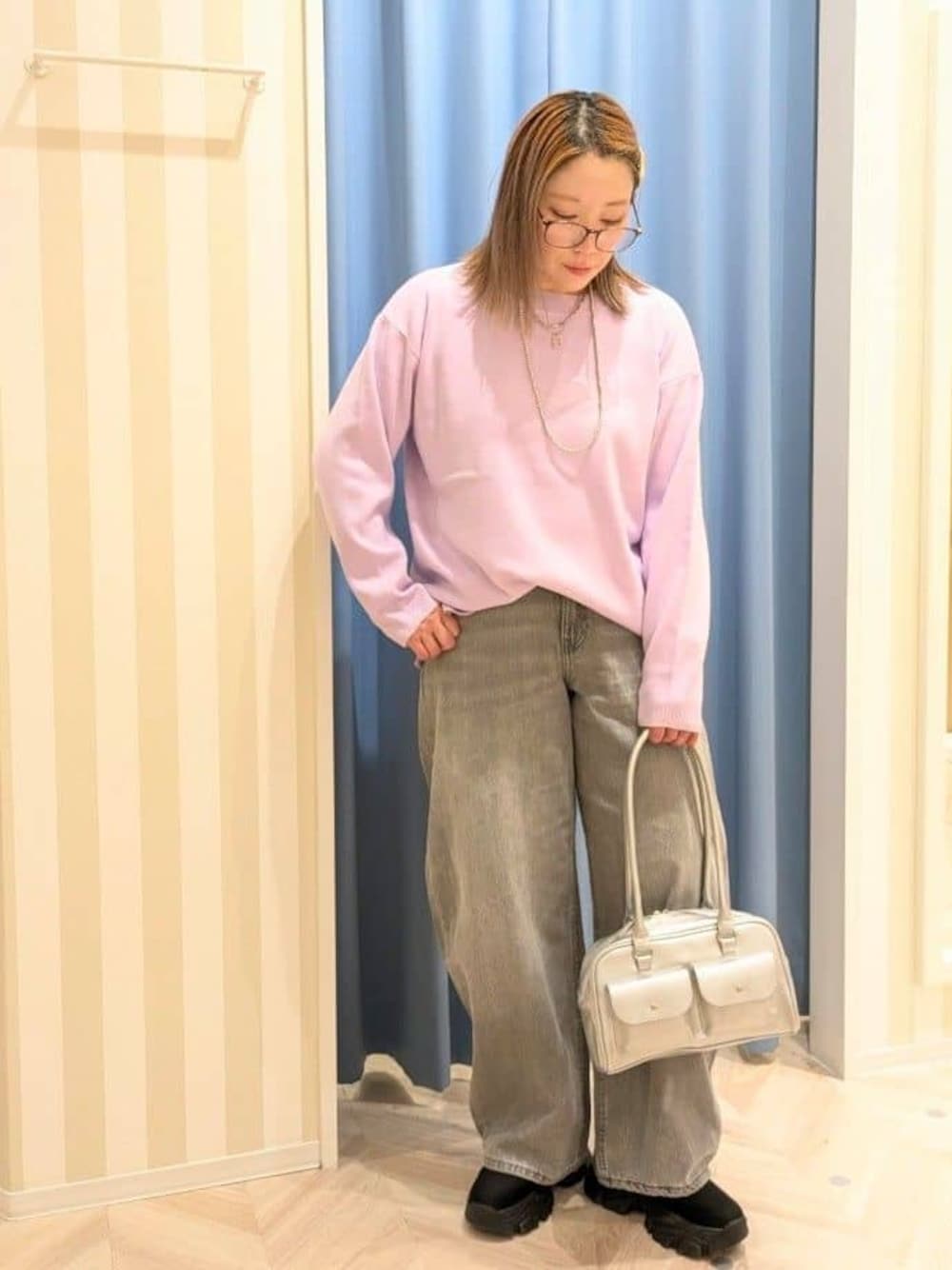 パープル系のニット/セーター、グレー系のデニムパンツ、シルバー系のボストンバッグを着用したレディースの冬コーディネートの1枚目の写真