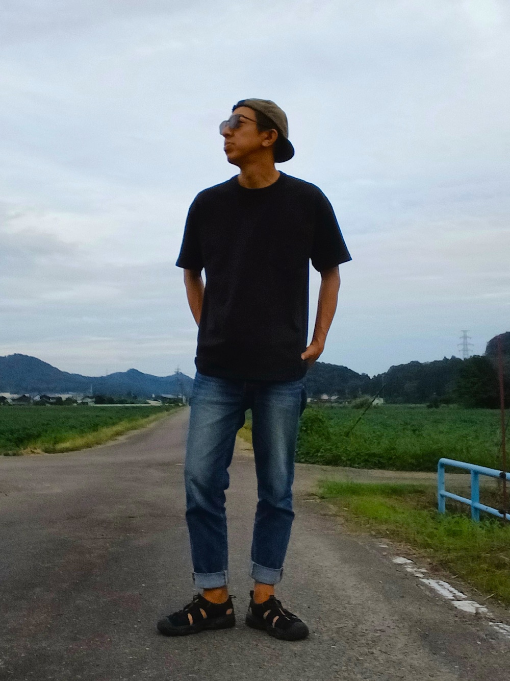 ブラック系のTシャツ/カットソー、ブルー系のデニムパンツ、ブラック系のサンダルを着用したメンズの秋コーディネートの1枚目の写真