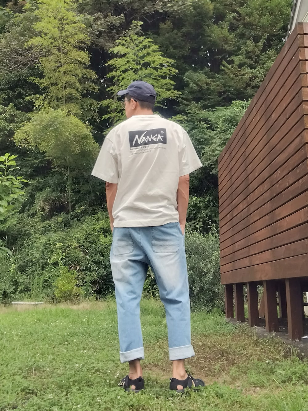 ホワイト系のTシャツ/カットソー、ブルー系のデニムパンツ、ブラック系のサンダルを着用したメンズの夏コーディネートの1枚目の写真