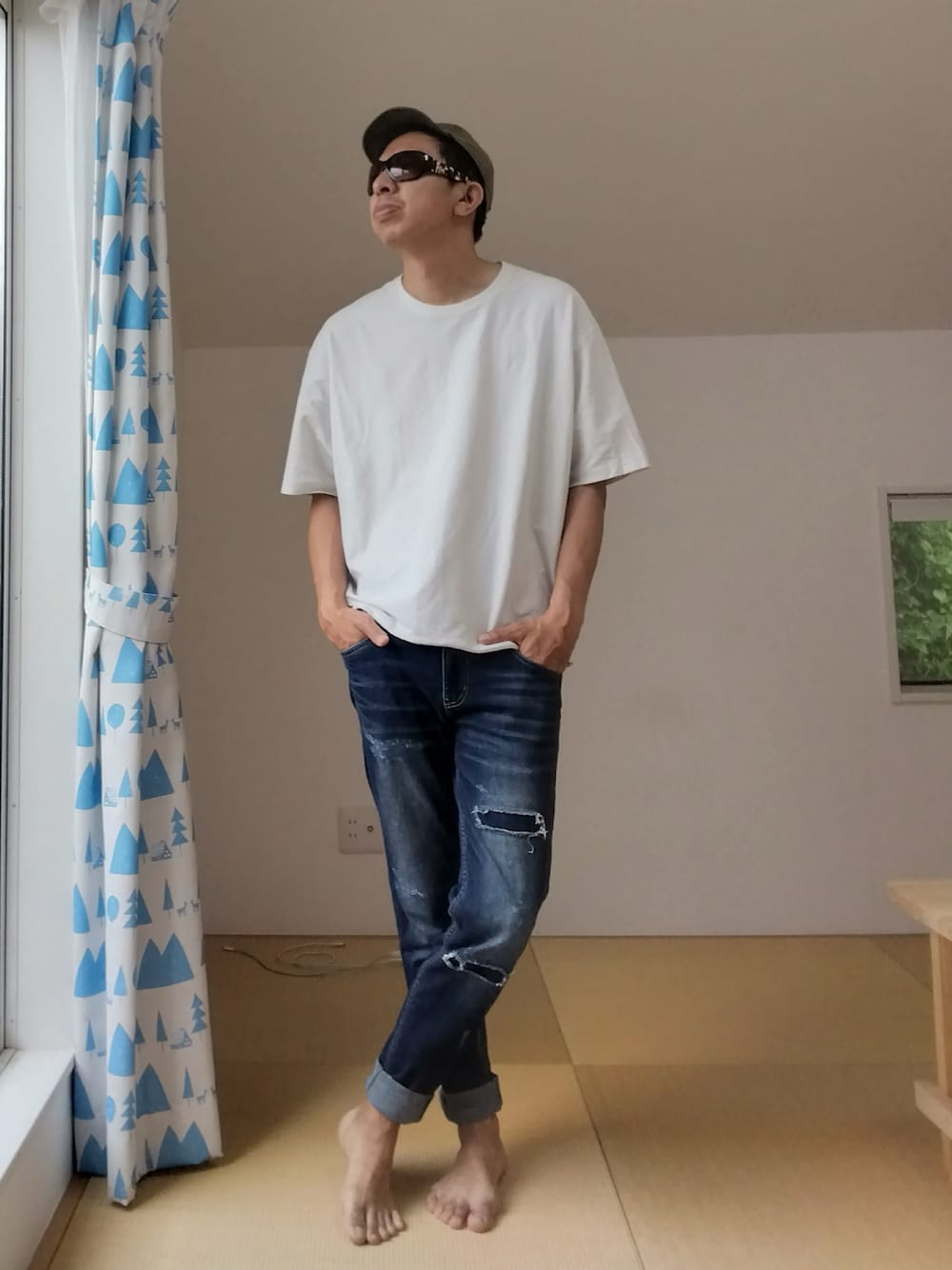 ホワイト系のTシャツ/カットソー、ブルー系のデニムパンツ、グリーン系のキャップを着用したメンズの春コーディネートの1枚目の写真