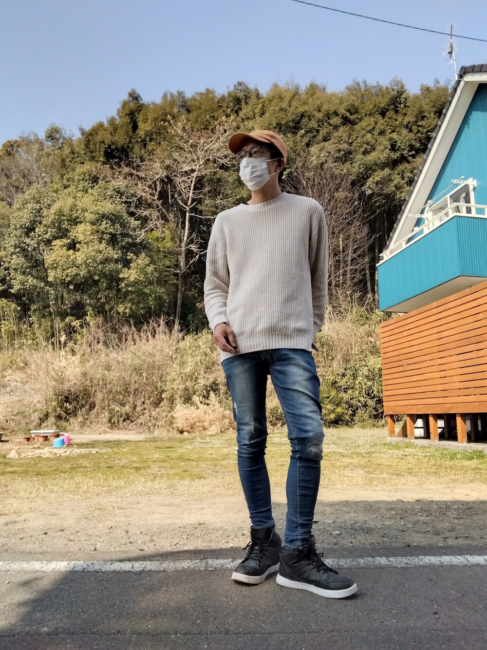 ベージュ系のニット/セーター、ブルー系のデニムパンツ、ブラック系のスニーカーを着用したメンズの春コーディネートの1枚目の写真