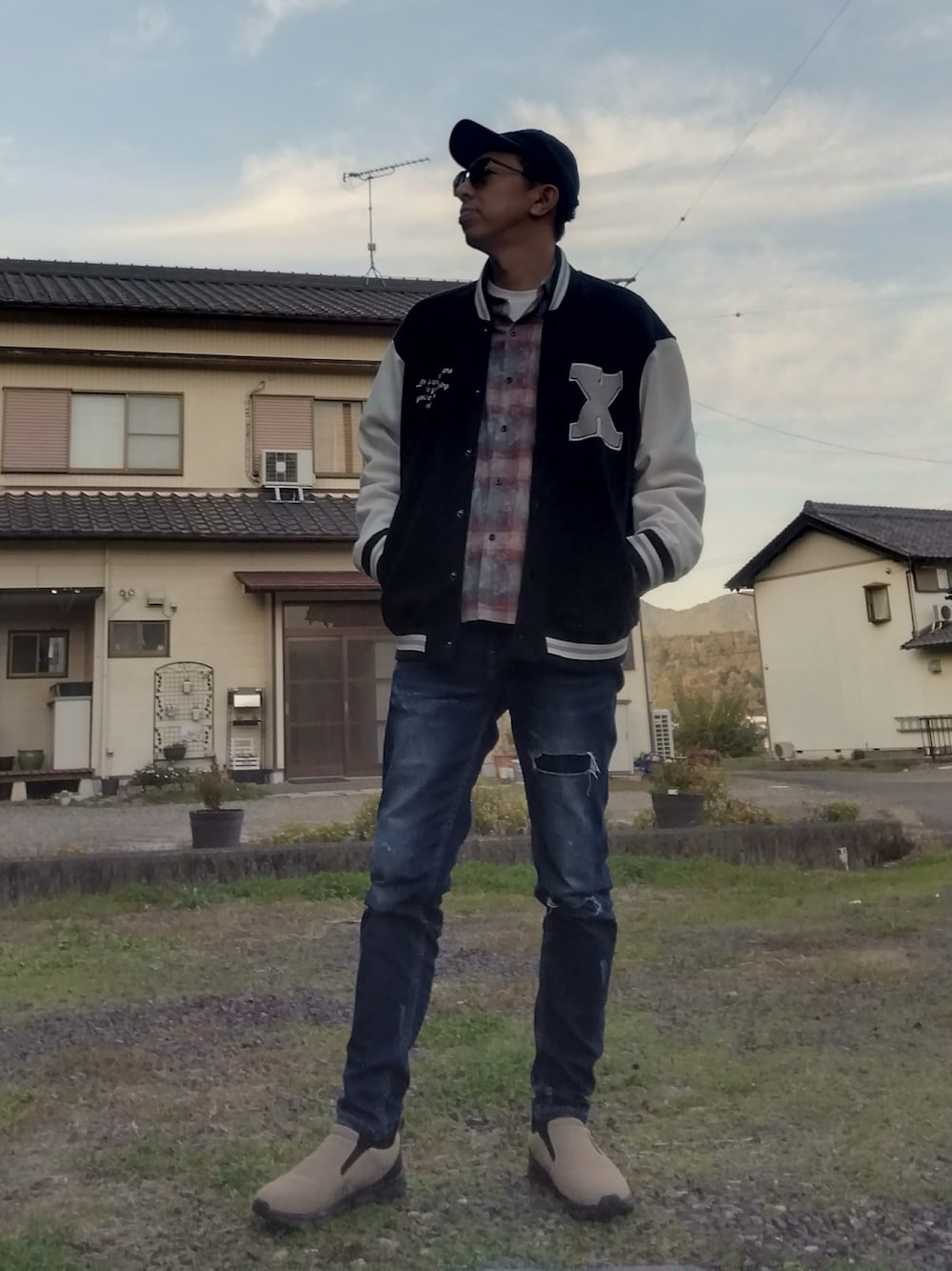 ブラック系のスタジャン、レッド系のシャツ/ブラウス、ブルー系のデニムパンツを着用したメンズの秋コーディネートの1枚目の写真