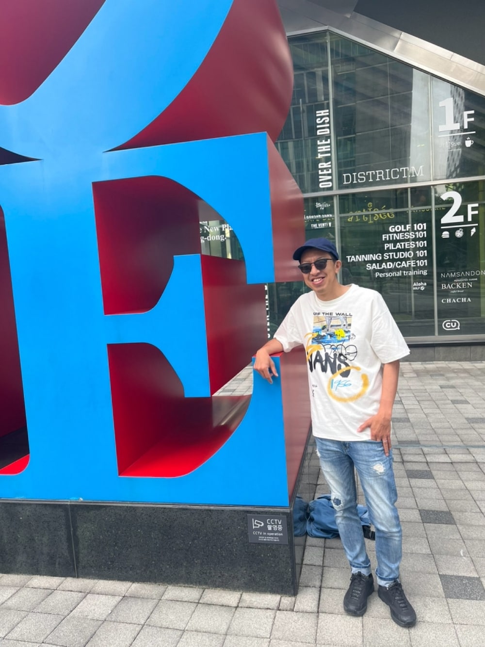 ホワイト系のTシャツ/カットソー、ブルー系のデニムパンツ、ブラック系のスニーカーを着用したメンズの春コーディネートの1枚目の写真