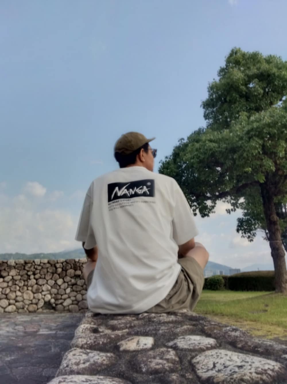 ホワイト系のTシャツ/カットソー、グリーン系のキャップを着用したメンズの夏コーディネートの1枚目の写真