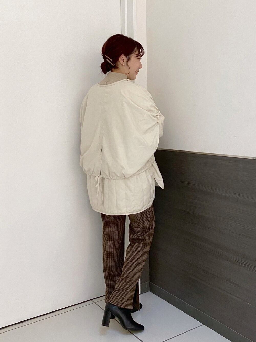 ブラック系のブーツ、ブラウン系のスラックス、ホワイト系のニット/セーターを着用したレディースの秋コーディネートの1枚目の写真