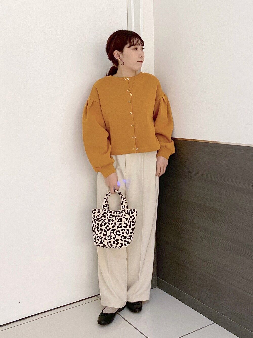 ブラック系のトートバッグ、オレンジ系のカーディガン/ボレロ、ホワイト系のその他パンツを着用したレディースの冬コーディネートの1枚目の写真