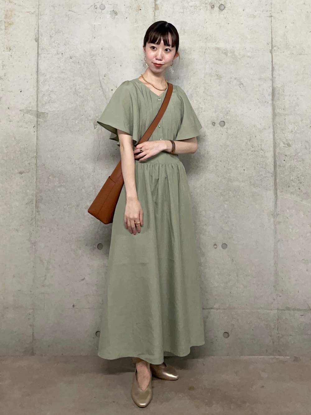 ゴールド系のパンプス、ブラウン系のショルダーバッグ、グリーン系のワンピースを着用したレディースの夏コーディネートの1枚目の写真