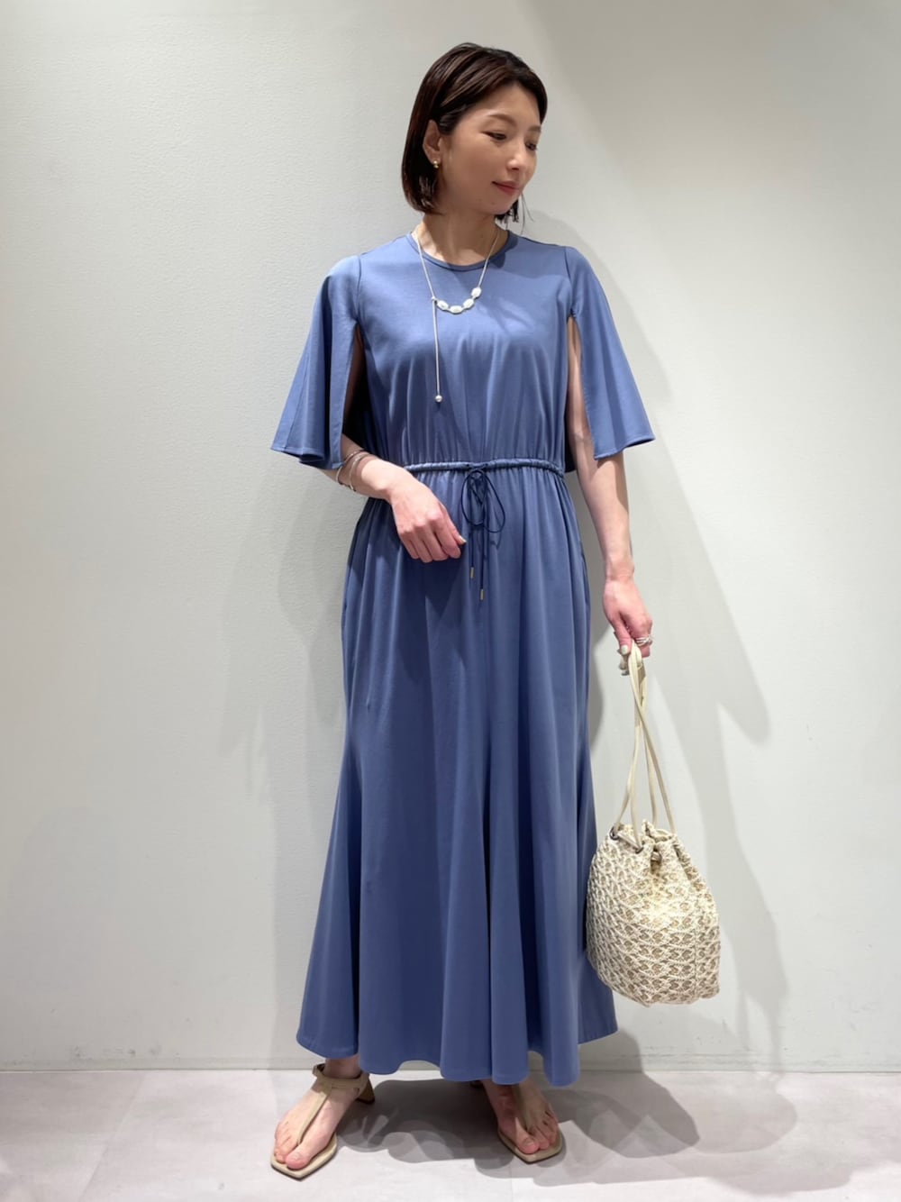 ブルー系のワンピース、ホワイト系のショルダーバッグ、シルバー系のネックレスを着用したレディースの春コーディネートの1枚目の写真