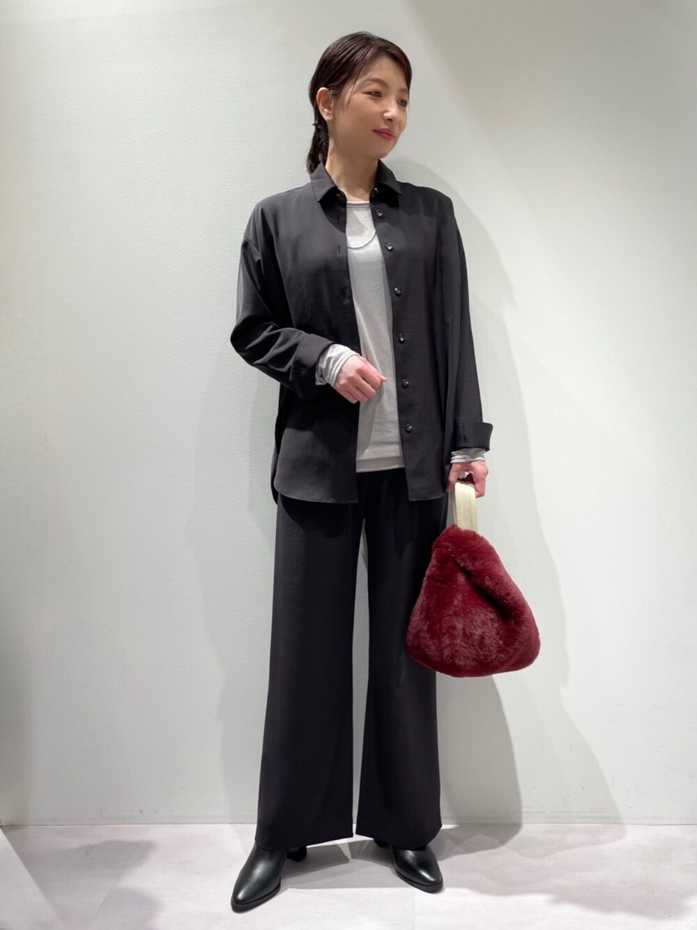 ブラック系のスラックス、ブラウン系のトートバッグ、ブラック系のブーツを着用したレディースの秋コーディネートの1枚目の写真