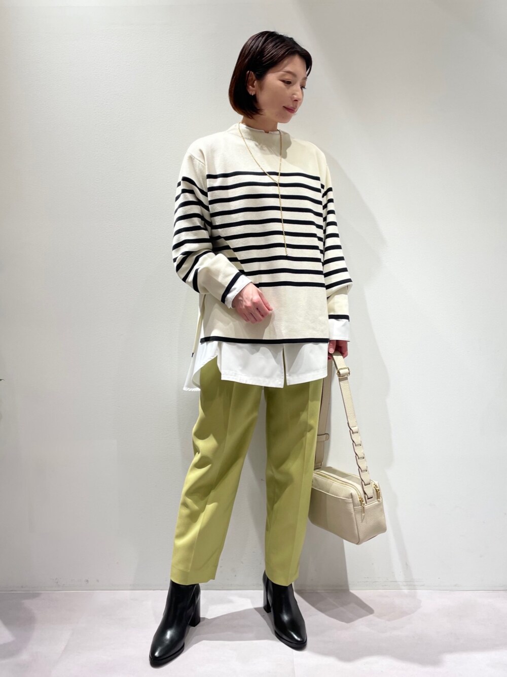 ホワイト系のシャツ/ブラウス、イエロー系のスラックス、ホワイト系のショルダーバッグを着用したレディースの冬コーディネートの1枚目の写真