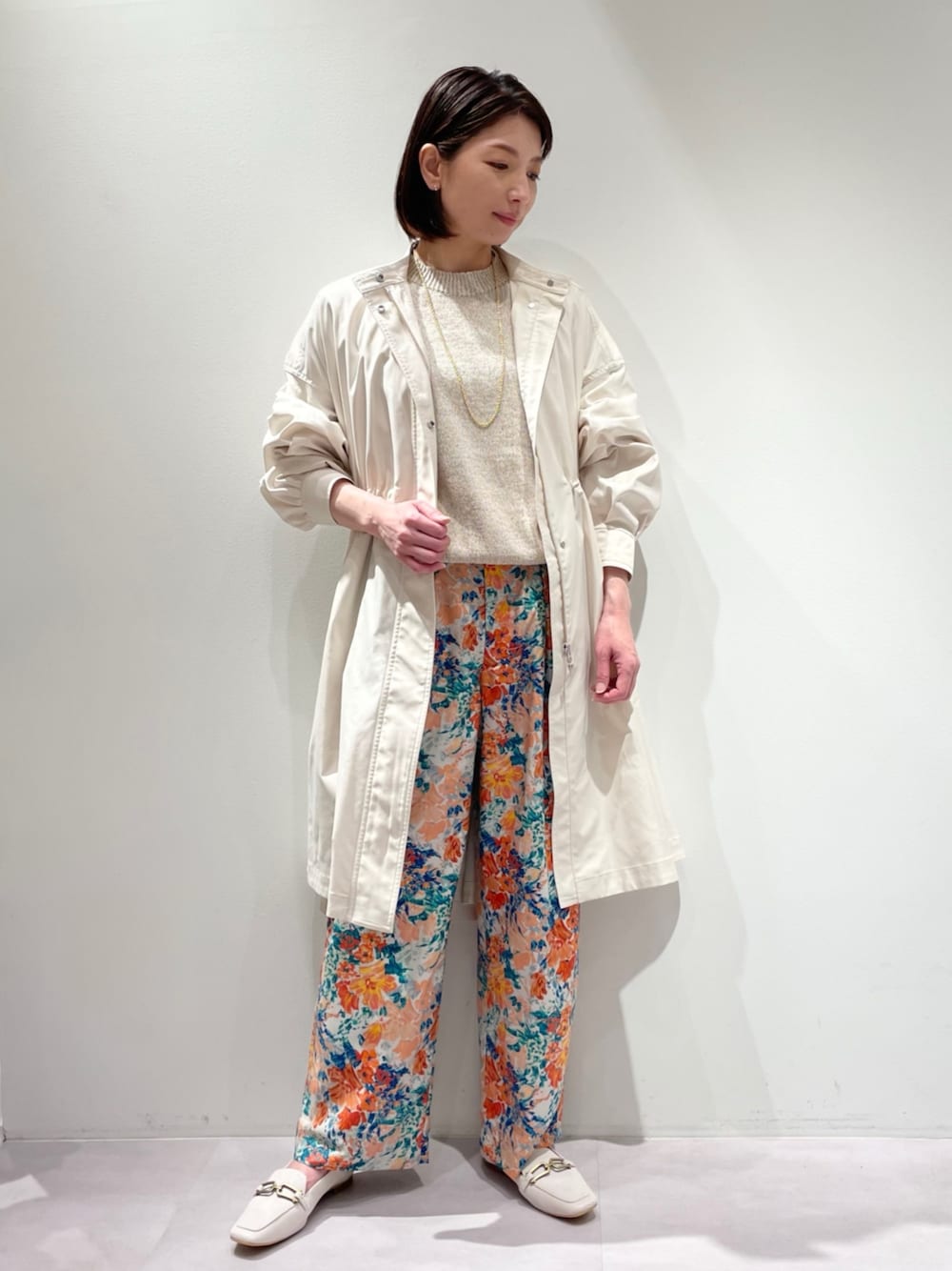 ベージュ系のニット/セーター、ホワイト系のマウンテンパーカー、グレー系のその他パンツを着用したレディースの春コーディネートの1枚目の写真