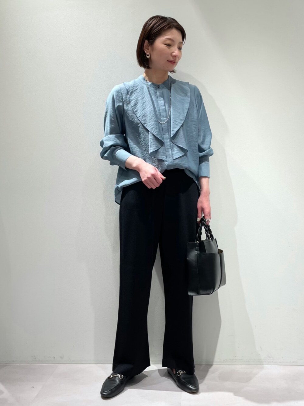 「カリテ(qualite)、LOWELL things、オフィスカジュアル、通勤コーデ、ブラウスコーデ、ブルーグレー、ニットパンツ、ウエストゴム、ショルダーバッグ、上品カジュアル、シア―ブラウス、ラッフルブラウス、ワイトパンツ、綺麗めカジュアル、大人コーデ」｜「qualiteの【一枚で華やぐ、エレガントな春ブラウス】レイヤードラッフルブラウス（シャツ/ブラウス、ブルー系）」を使った、KAWAMURAさん（レディース・160cm）の春コーディネートの1枚目の写真