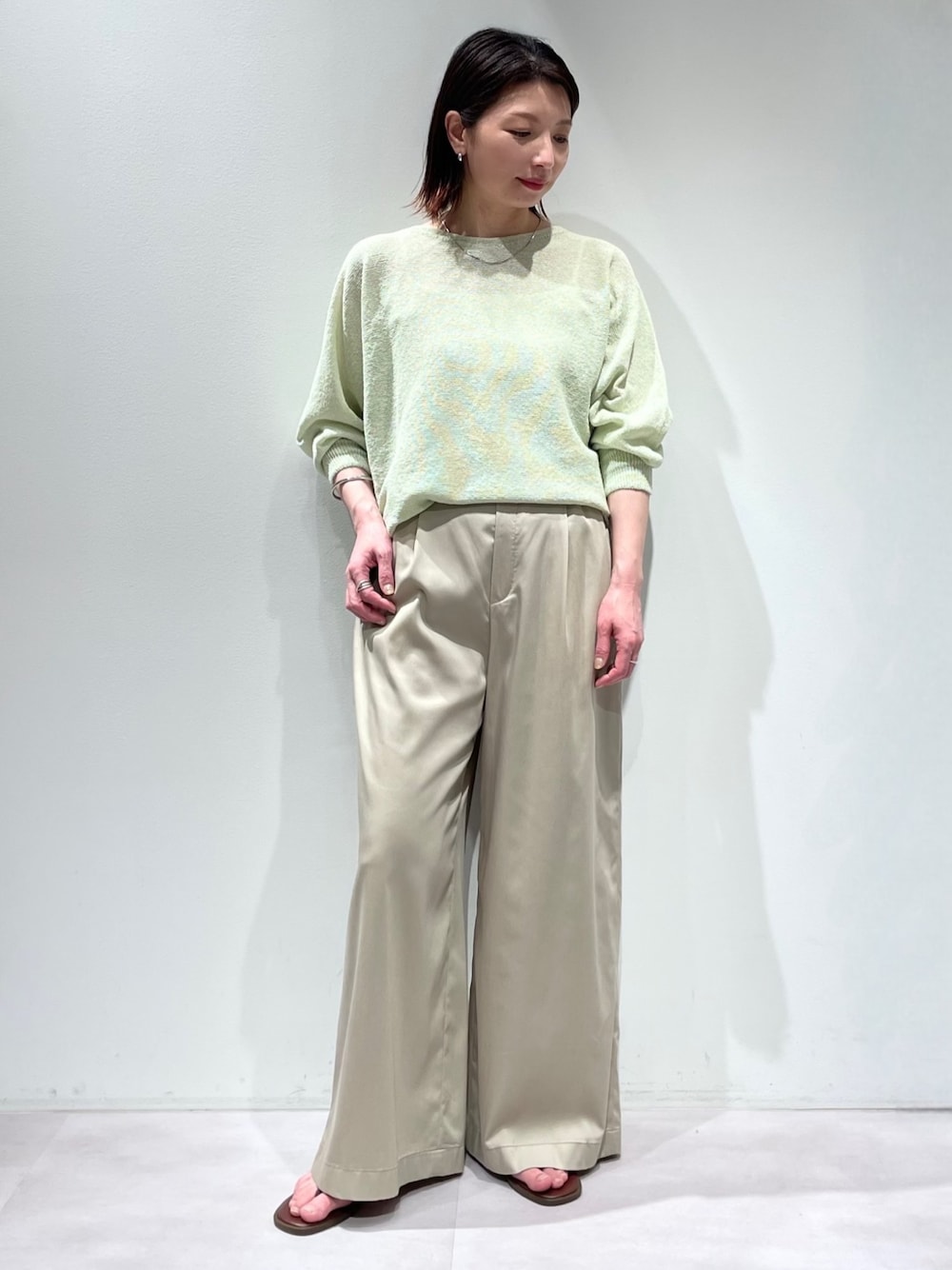 グリーン系のニット/セーター、ベージュ系のその他パンツ、シルバー系のネックレスを着用したレディースの春コーディネートの1枚目の写真