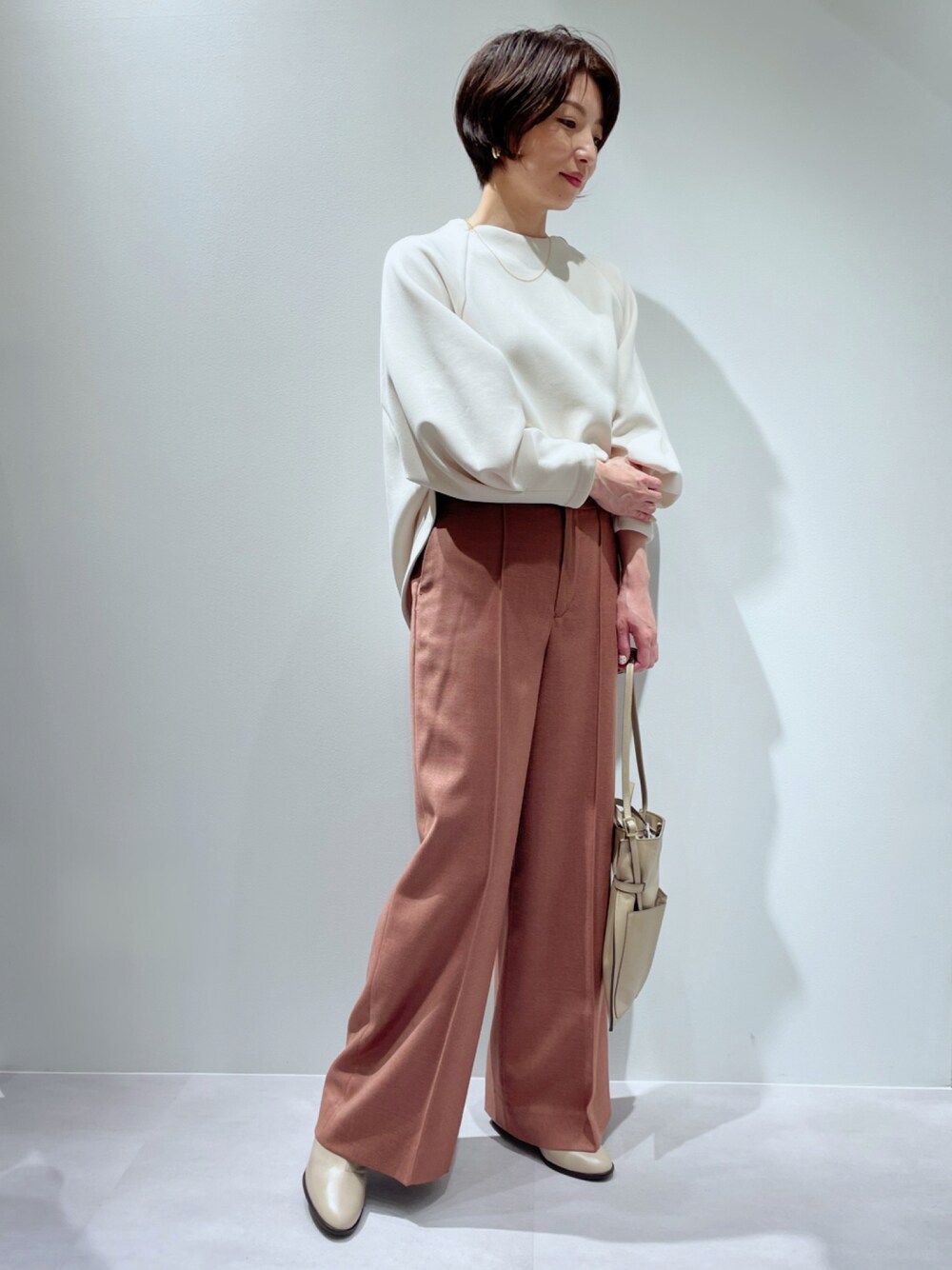 オレンジ系のその他パンツ、ベージュ系のスウェット、ベージュ系のブーツを着用したレディースの秋コーディネートの1枚目の写真