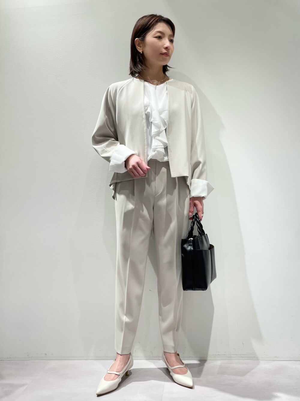 ホワイト系のシャツ/ブラウス、ブラック系のトートバッグ、ベージュ系のスラックスを着用したレディースの冬コーディネートの1枚目の写真