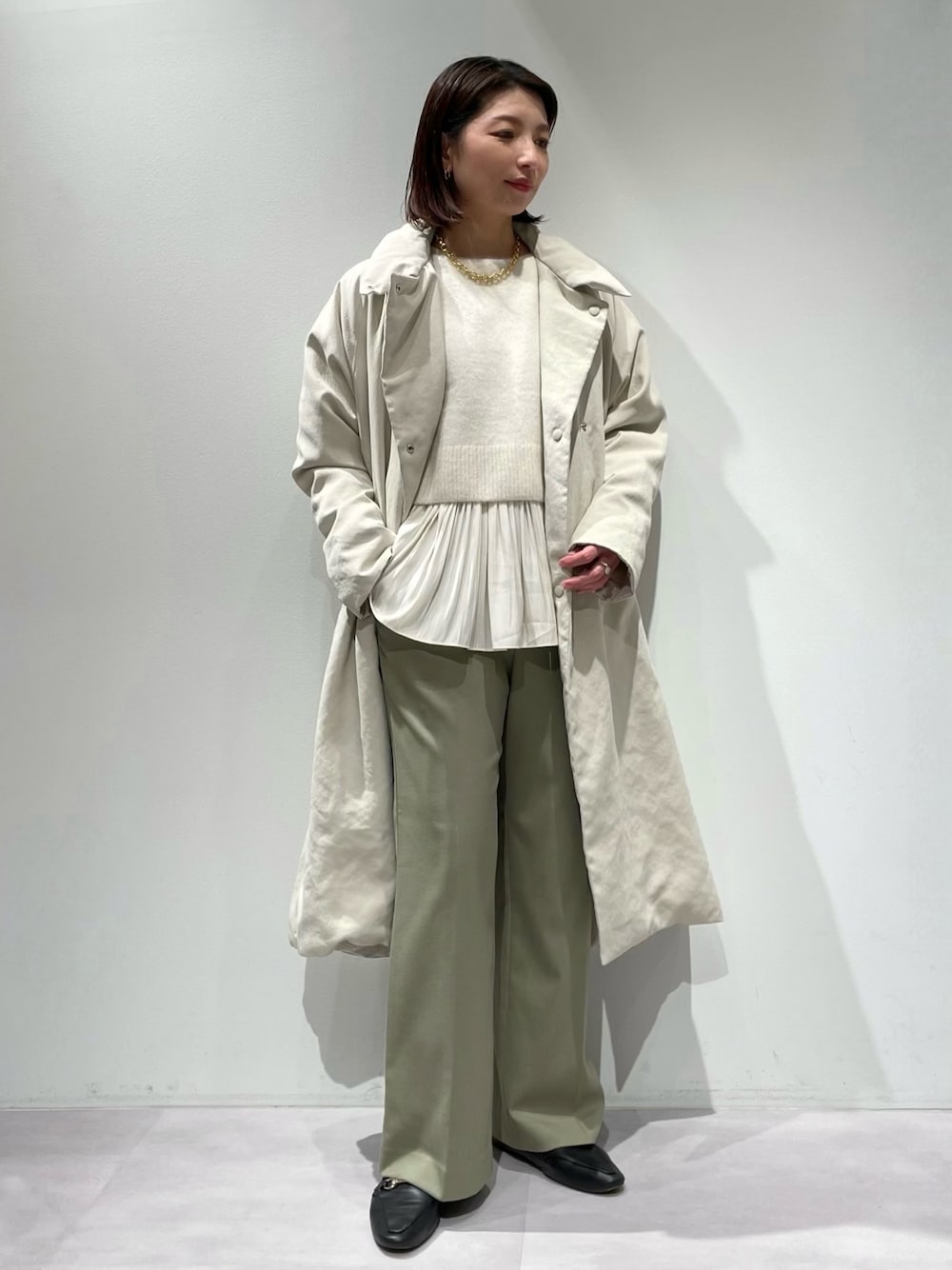 グリーン系のその他パンツ、ベージュ系のダウンジャケット/コート、ホワイト系のニット/セーターを着用したレディースの秋コーディネートの1枚目の写真