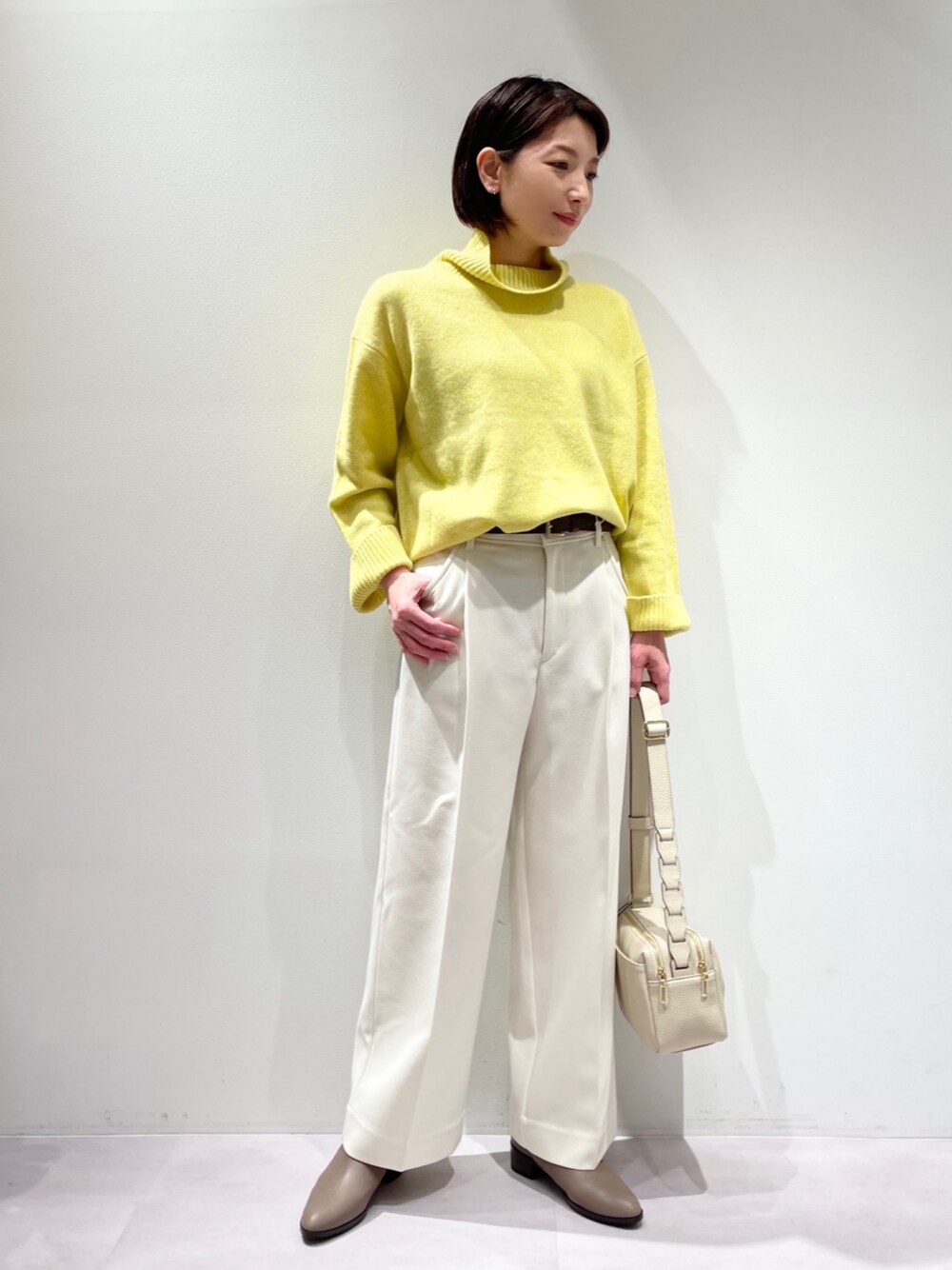 イエロー系のニット/セーター、ホワイト系のその他パンツ、ベージュ系のブーツを着用したレディースの冬コーディネートの1枚目の写真