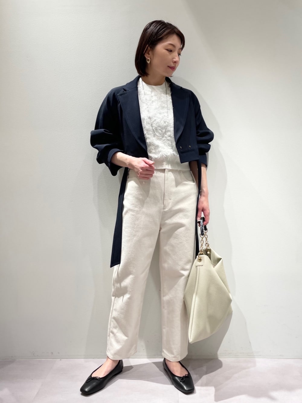 ブルー系のトレンチコート、ホワイト系のデニムパンツ、ホワイト系のトートバッグを着用したレディースの冬コーディネートの1枚目の写真