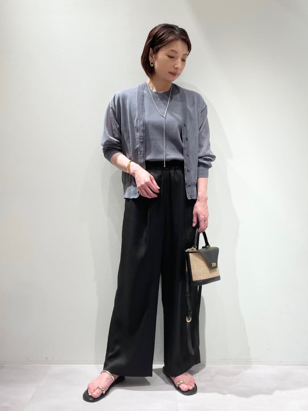 グレー系のシャツ/ブラウス、グレー系のニット/セーター、ベージュ系のトートバッグを着用したレディースの春コーディネートの1枚目の写真