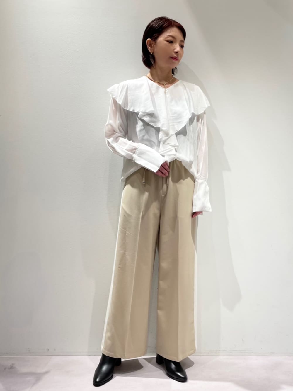 ベージュ系のその他パンツ、ホワイト系のシャツ/ブラウス、ブラック系のブーツを着用したレディースの秋コーディネートの1枚目の写真