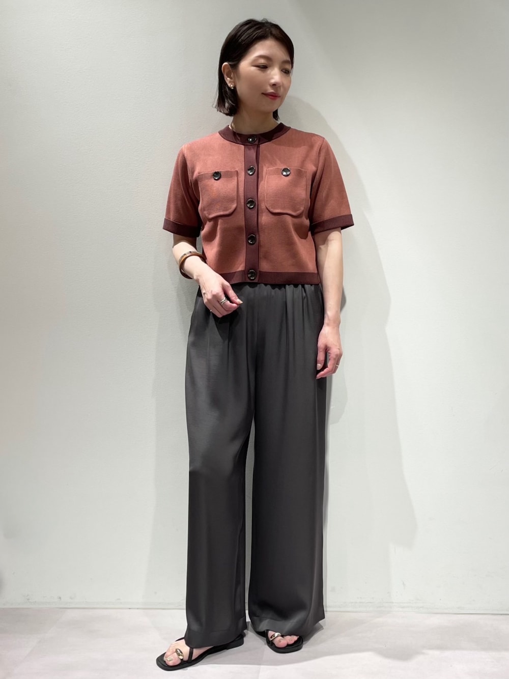 グレー系のその他パンツ、ピンク系のカーディガン/ボレロ、ブラウン系のネックレスを着用したレディースの夏コーディネートの1枚目の写真