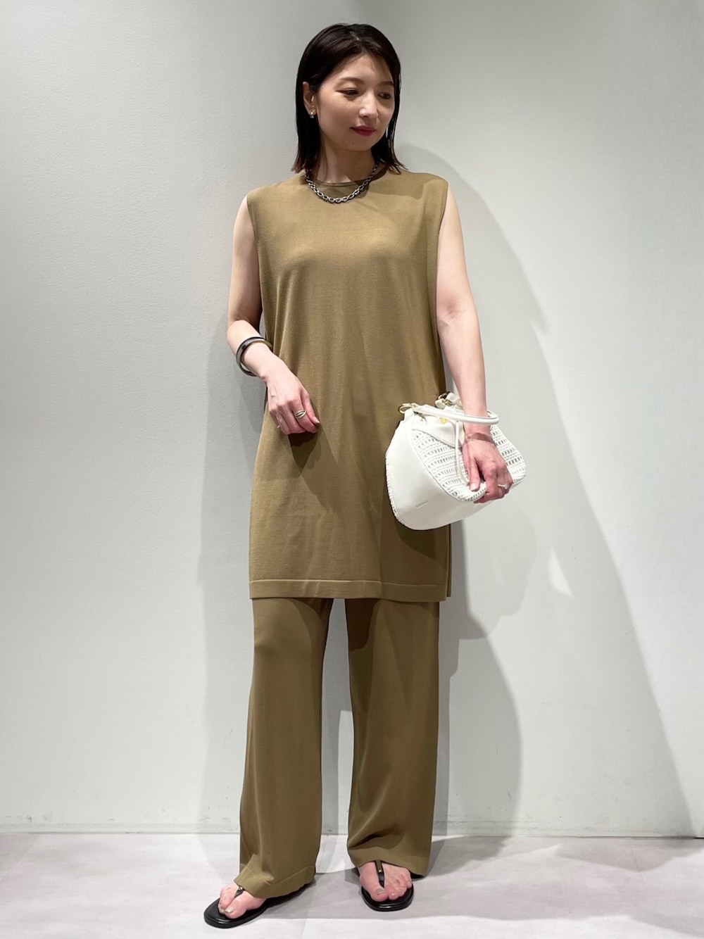 ベージュ系のその他パンツ、ベージュ系のニット/セーター、シルバー系のネックレスを着用したレディースの夏コーディネートの1枚目の写真