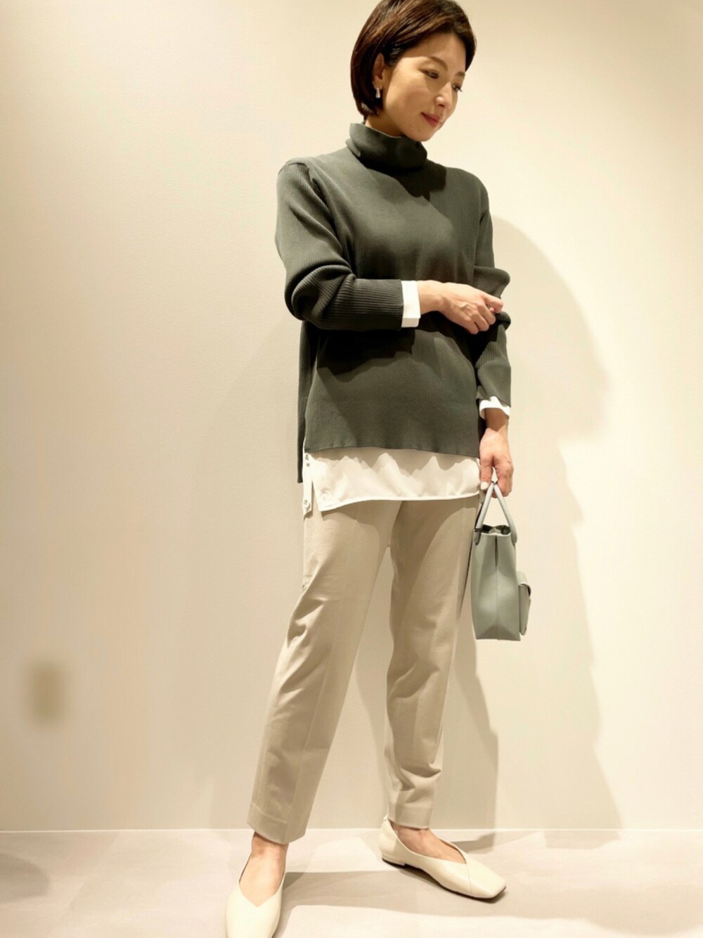 ベージュ系のその他パンツ、グリーン系のニット/セーター、ホワイト系のシャツ/ブラウスを着用したレディースの秋コーディネートの1枚目の写真