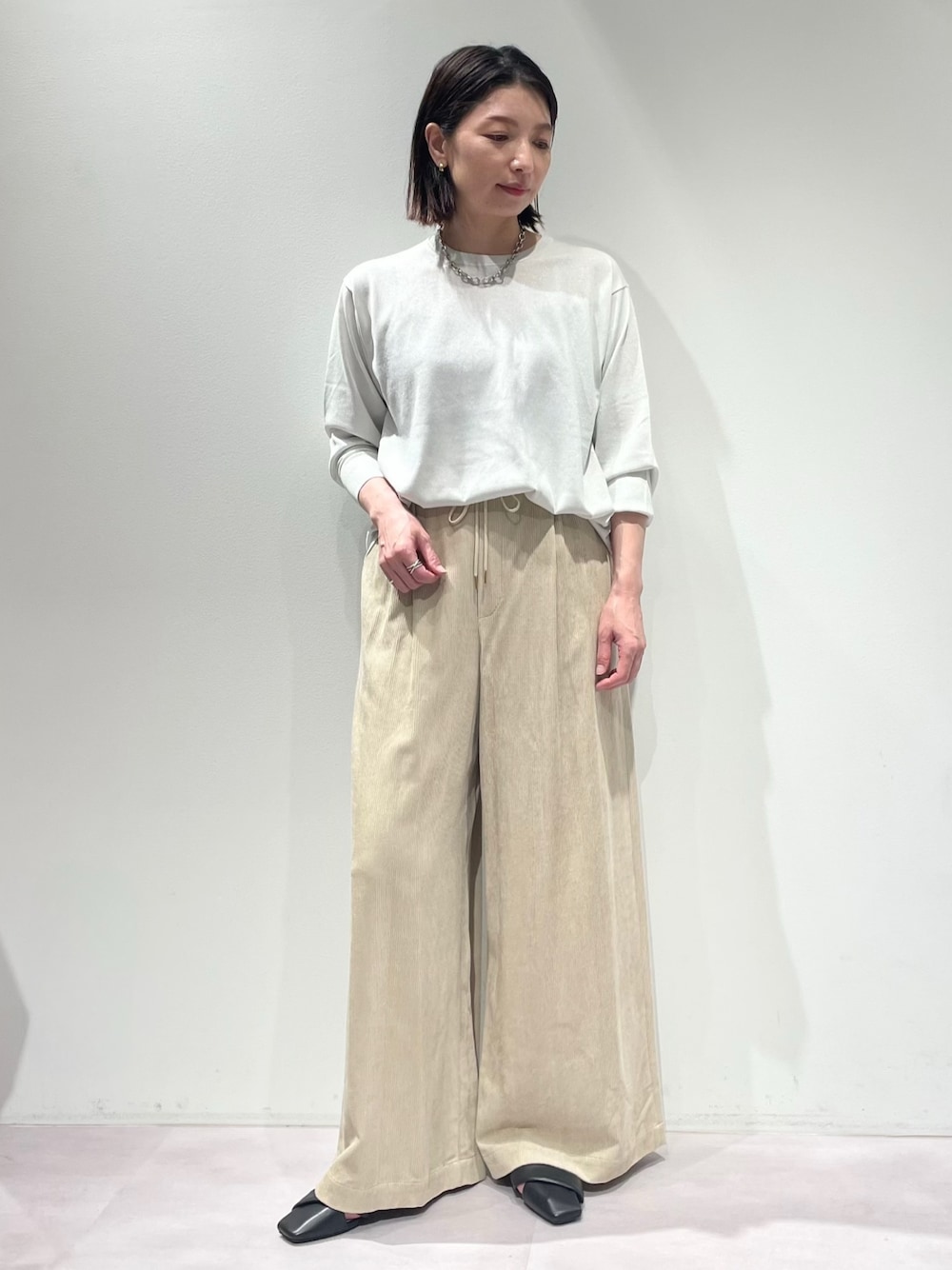 ベージュ系のその他パンツ、ホワイト系のニット/セーター、シルバー系のネックレスを着用したレディースの秋コーディネートの1枚目の写真