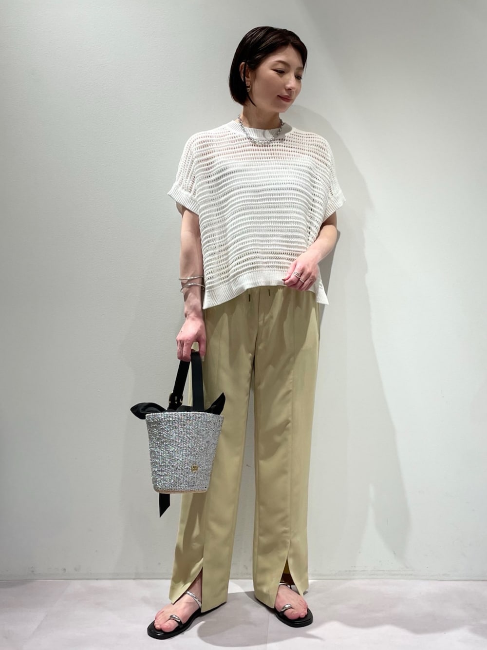 「カリテ(qualite)、パンツコーデ、透かし編みニット、スリットパンツ、ウエストゴム、ウエストドロスト、春夏コーデ、オフホワイトニット、オーカーグリーン、足長効果パンツ、大人カジュアル、お出かけコーデ、上品カジュアル、綺麗めパンツ、オフィスカジュアル」｜「qualiteのバックサテンジョーゼットベンツパンツ（スラックス、イエロー系）」を使った、KAWAMURAさん（レディース・160cm）の春コーディネートの1枚目の写真