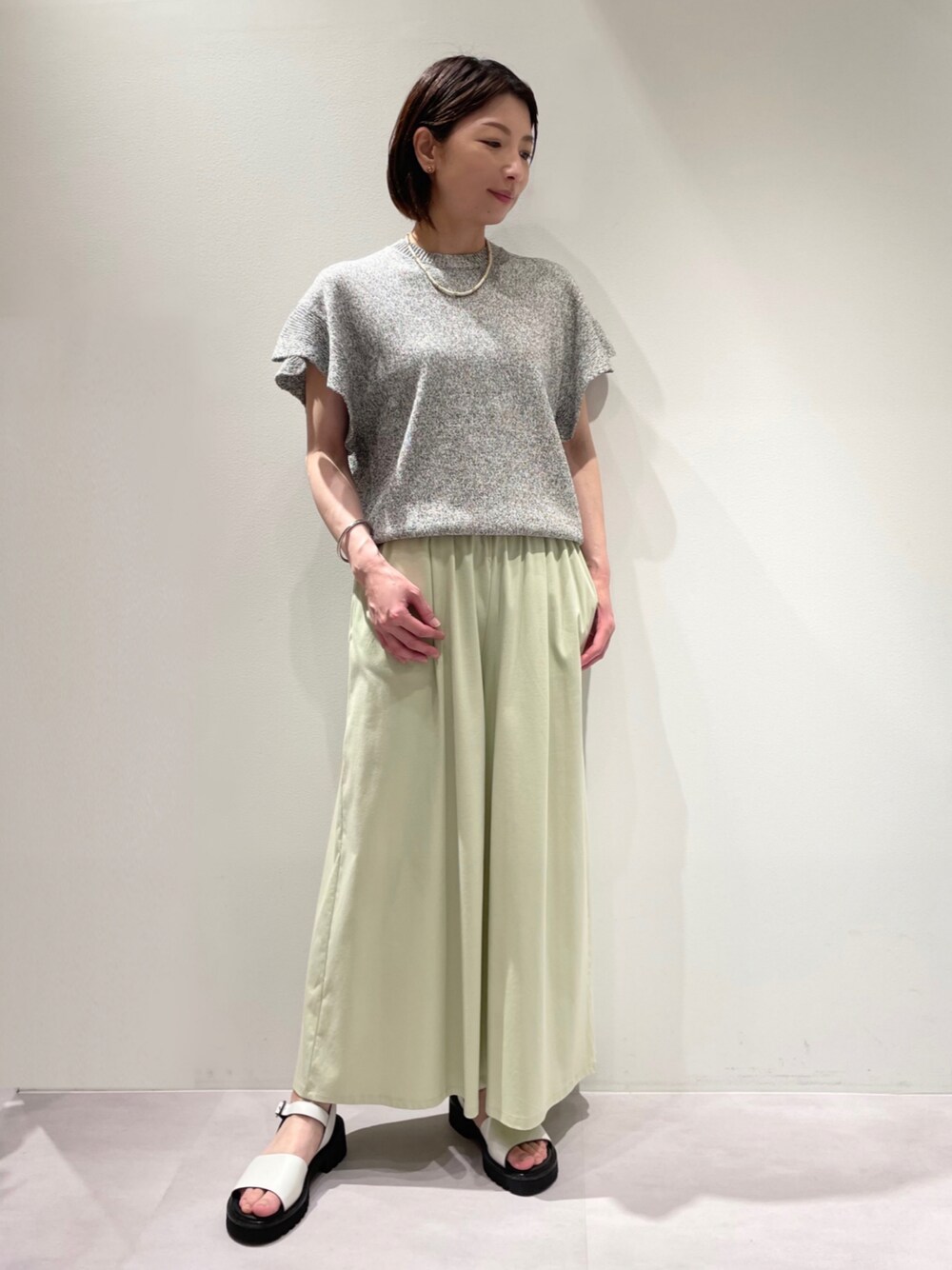 グリーン系のその他パンツ、グレー系のニット/セーターを着用したレディースの春コーディネートの1枚目の写真