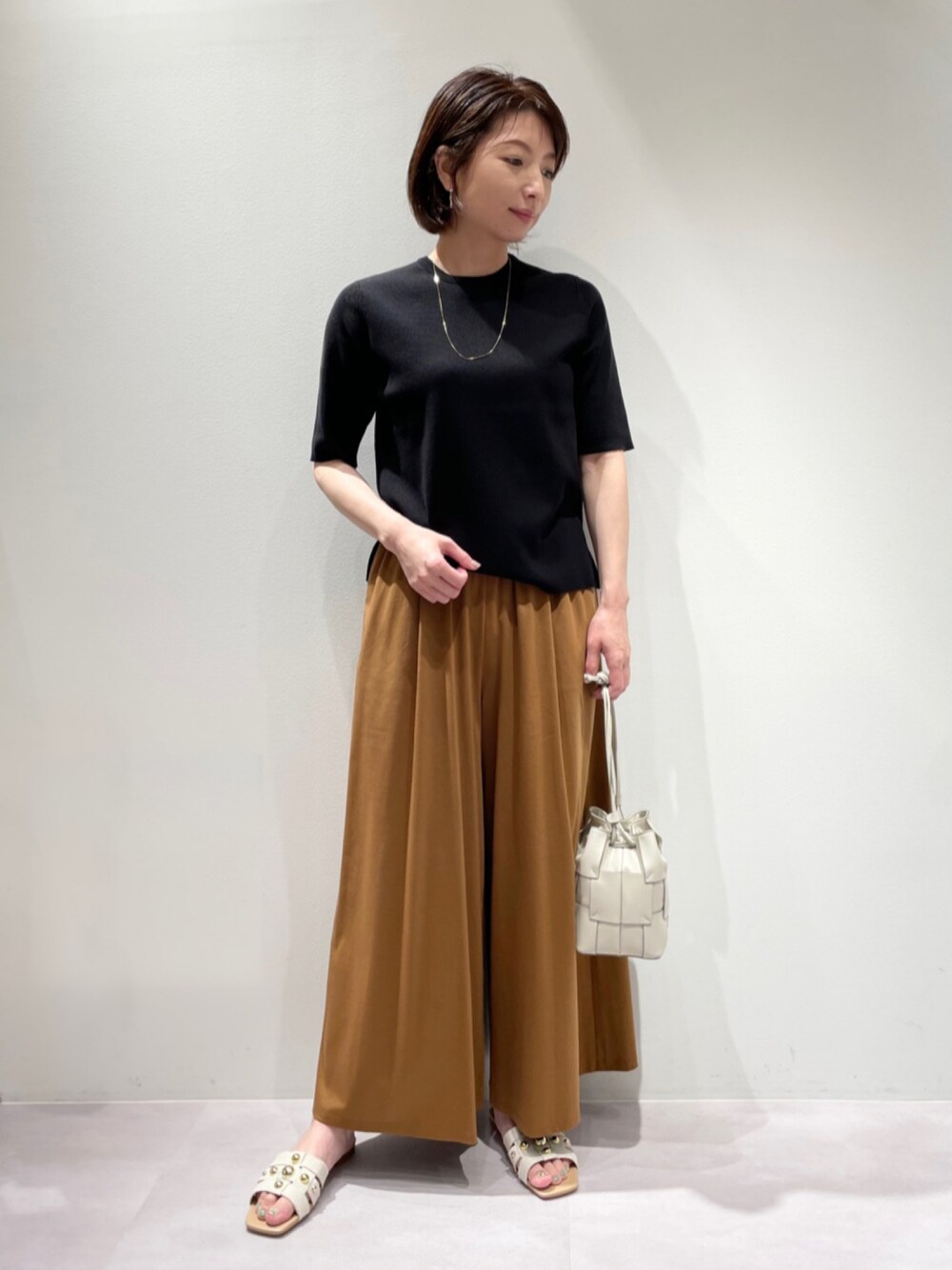 ブラック系のニット/セーター、イエロー系のその他パンツ、その他のサンダルを着用したレディースの夏コーディネートの1枚目の写真