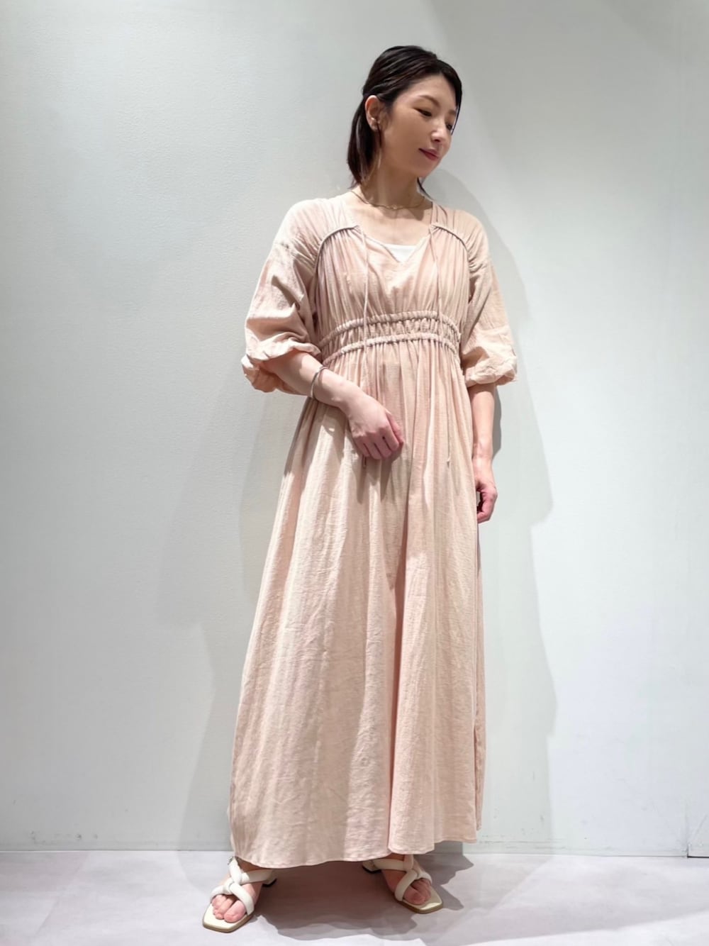 ホワイト系のサンダル、ホワイト系のキャミソール、ベージュ系のワンピースを着用したレディースの夏コーディネートの1枚目の写真